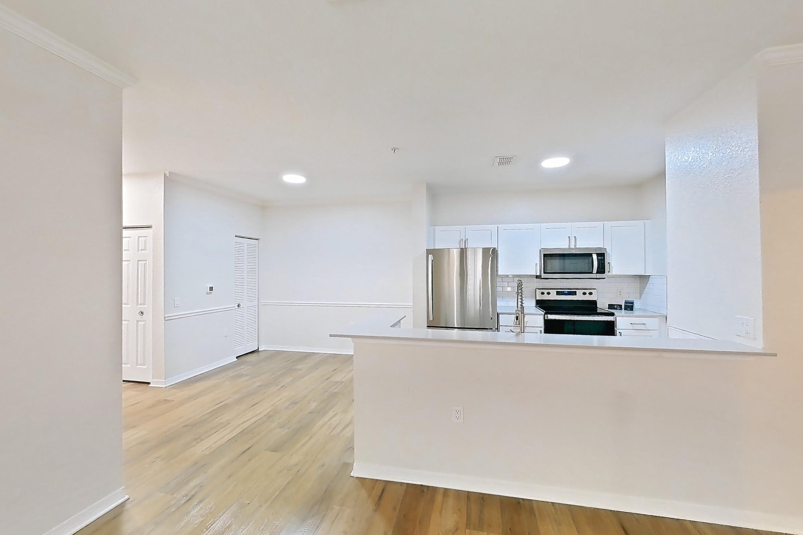 Living room with electric range, light wood-finish flooring, oven/range, refrigerator, and stainless steel appliances, Apartment 101 at Tortuga Bay
