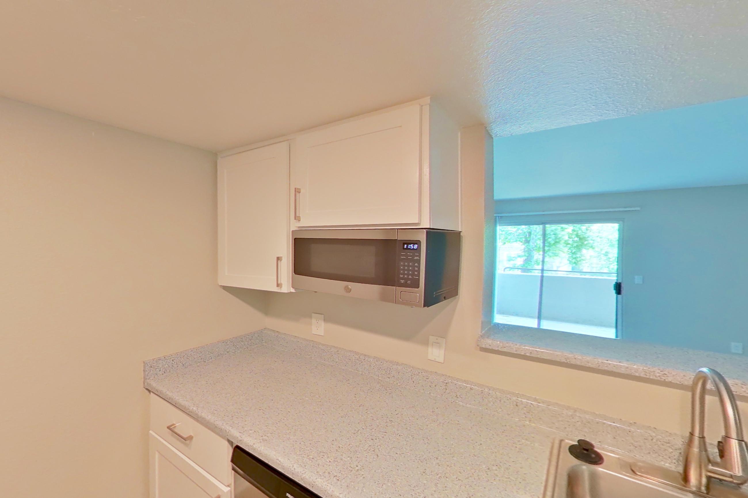 Kitchen with dishwasher, electric range, light stone countertops, light wood-finish flooring, microwave, oven/range, refrigerator, and stainless steel appliances, Apartment 08 at Avana Rancho Cucamonga