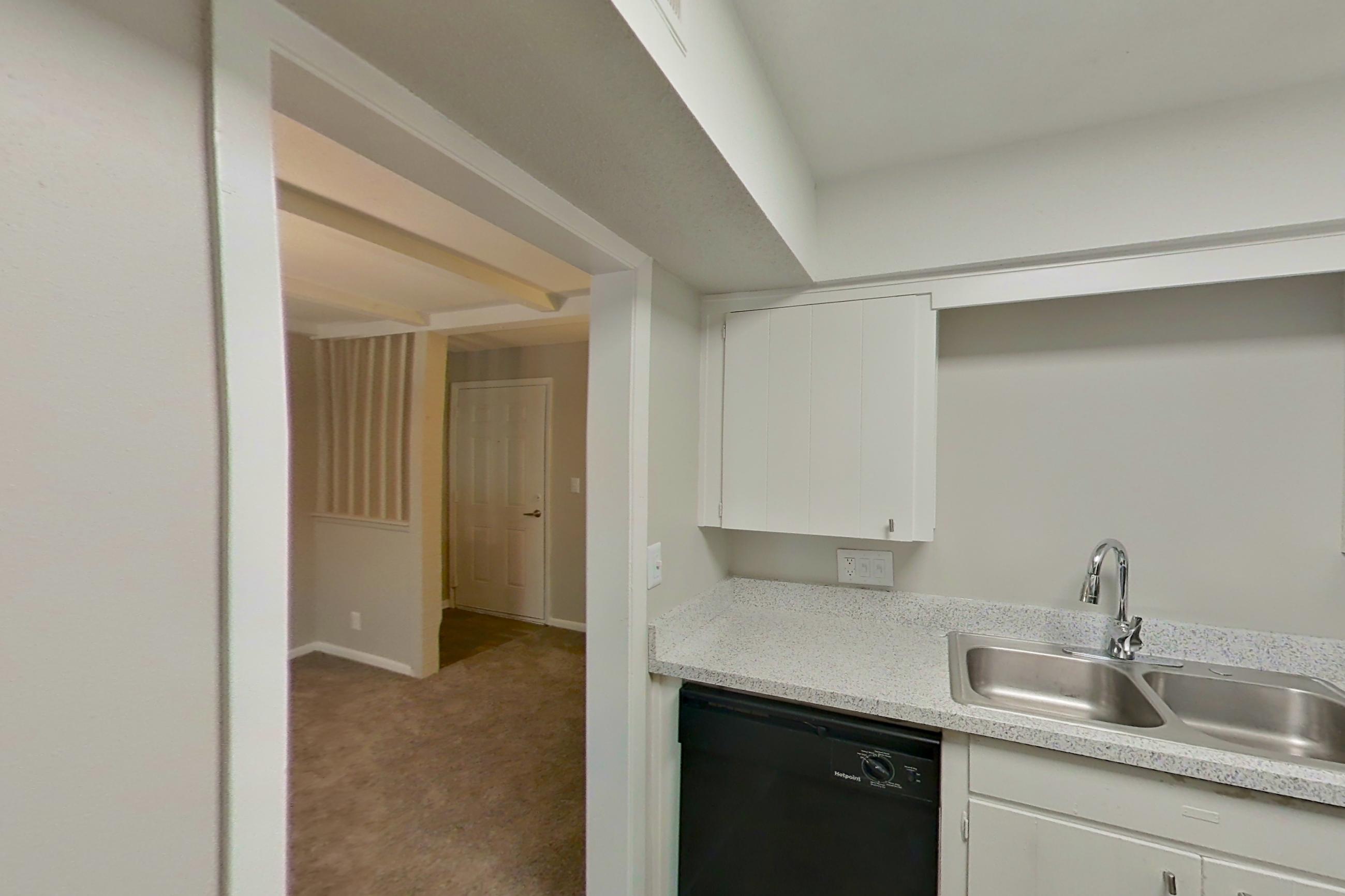 Kitchen with black appliances, dishwasher, electric range, light carpet, light countertops, light stone countertops, light wood-finish flooring, microwave, oven/range, and refrigerator, Apartment 1514C at The Life at Legacy Fountains