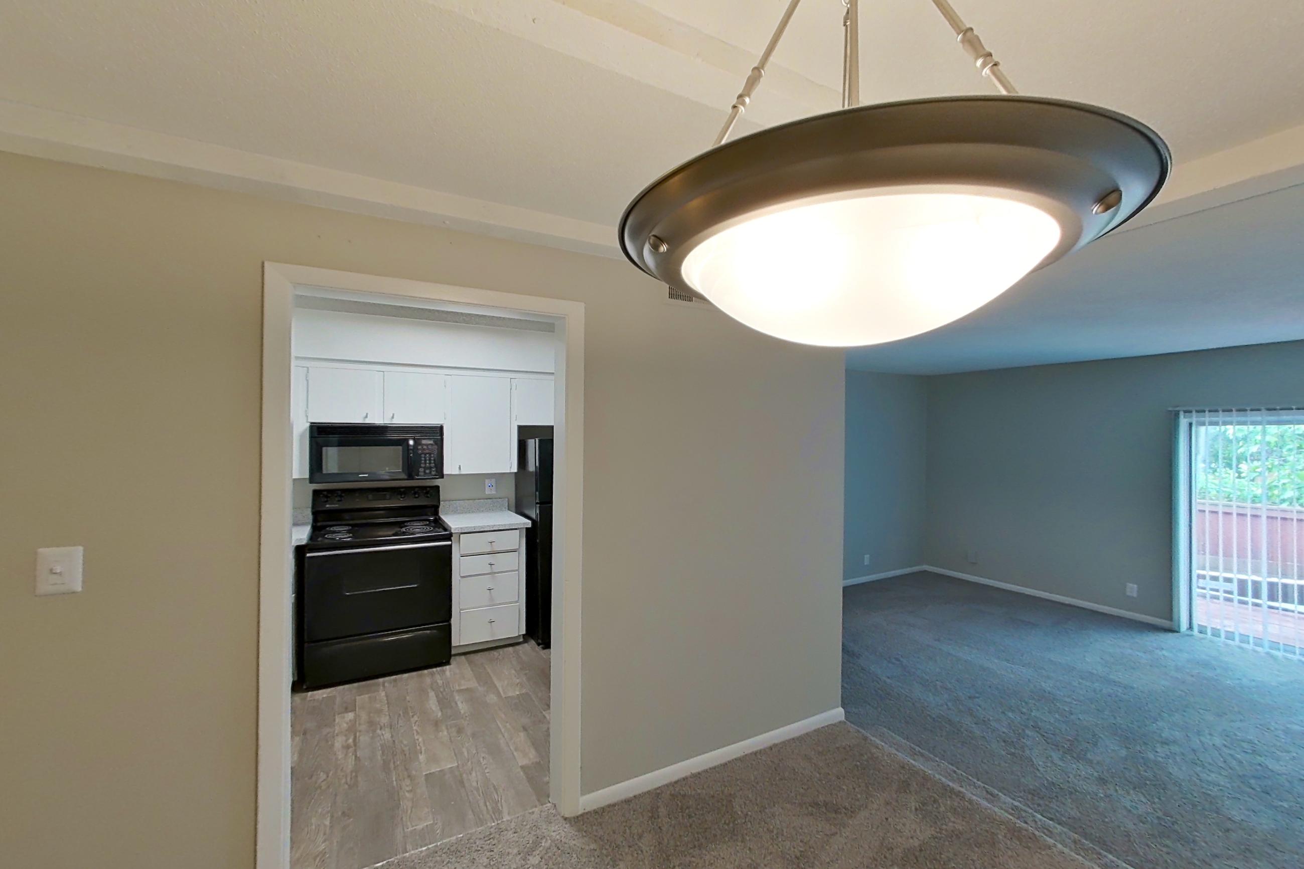 Living space with black appliances, electric range, light carpet, light countertops, and oven/range, Apartment 1514C at The Life at Legacy Fountains