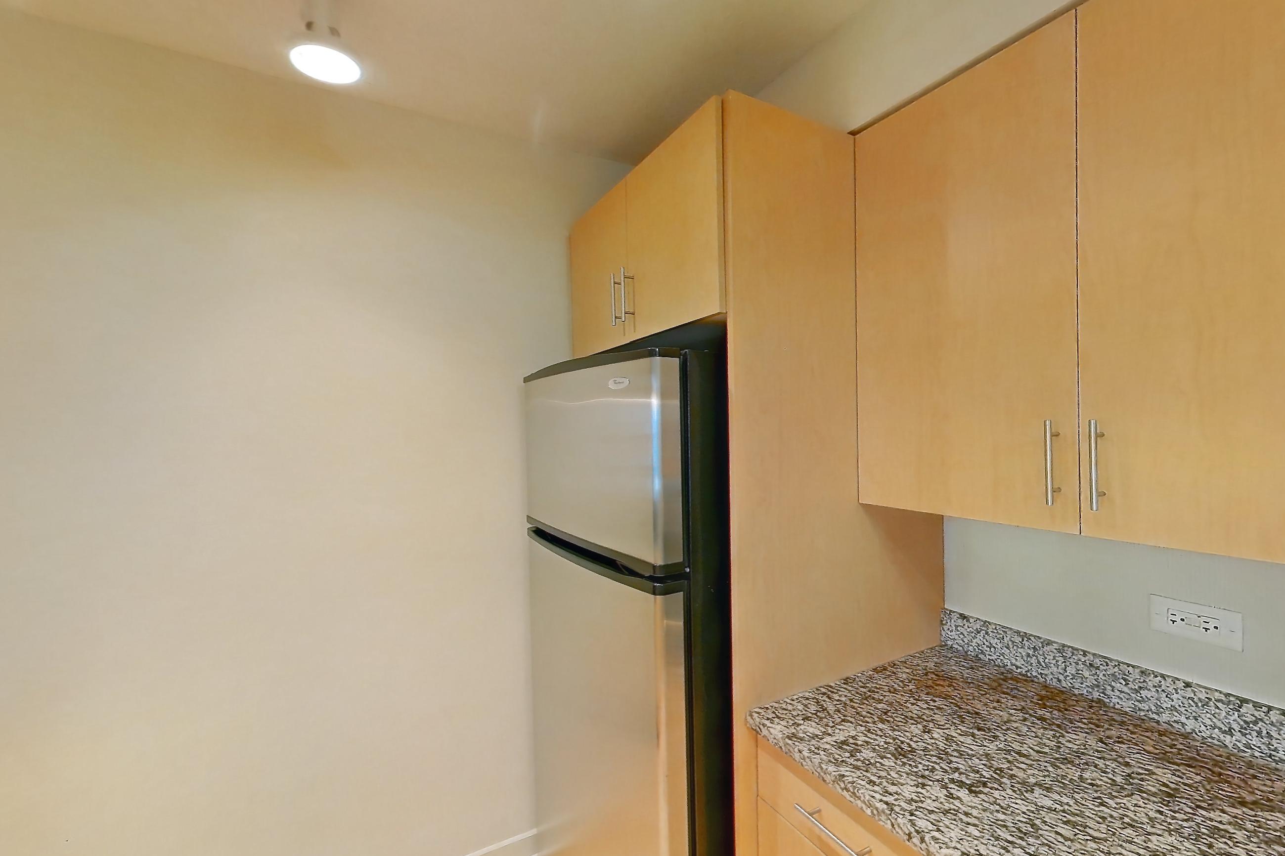 Kitchen with dishwasher, electric range, light countertops, light stone countertops, light wood-finish flooring, oven/range, refrigerator, and stainless steel appliances, Apartment 00-1404 at Sky55