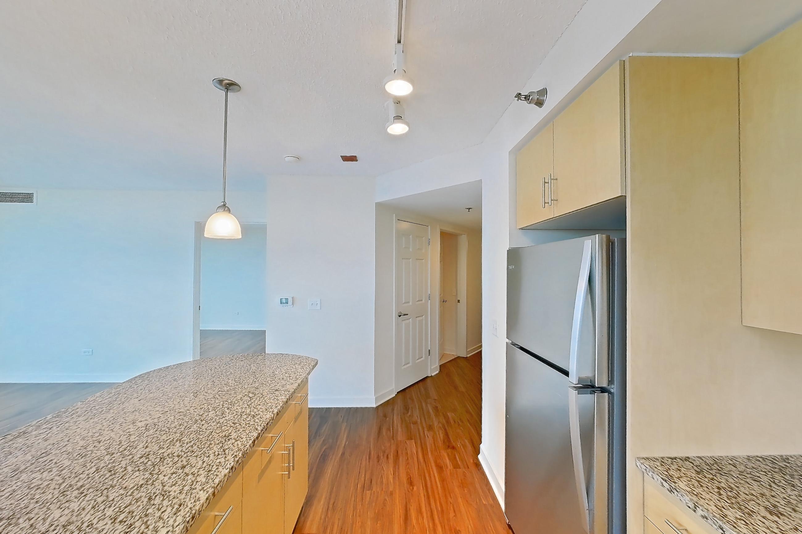 Kitchen with dishwasher, electric range, light countertops, light stone countertops, light wood-finish flooring, microwave, oven/range, refrigerator, and stainless steel appliances, Apartment 00-1909 at Sky55