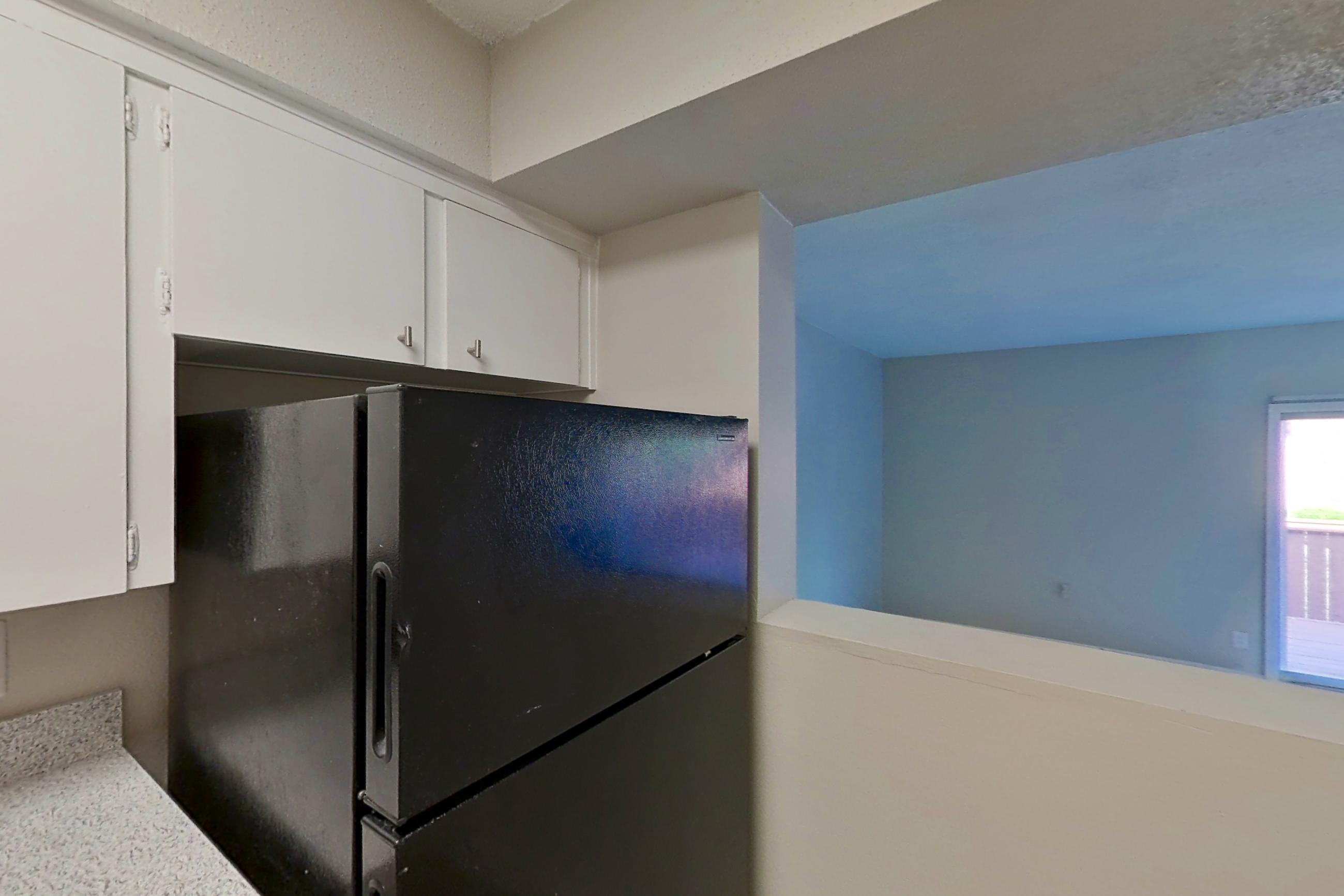 Kitchen with black appliances, dishwasher, electric range, light countertops, light wood-finish flooring, oven/range, and refrigerator, Apartment 1524C at The Life at Legacy Fountains