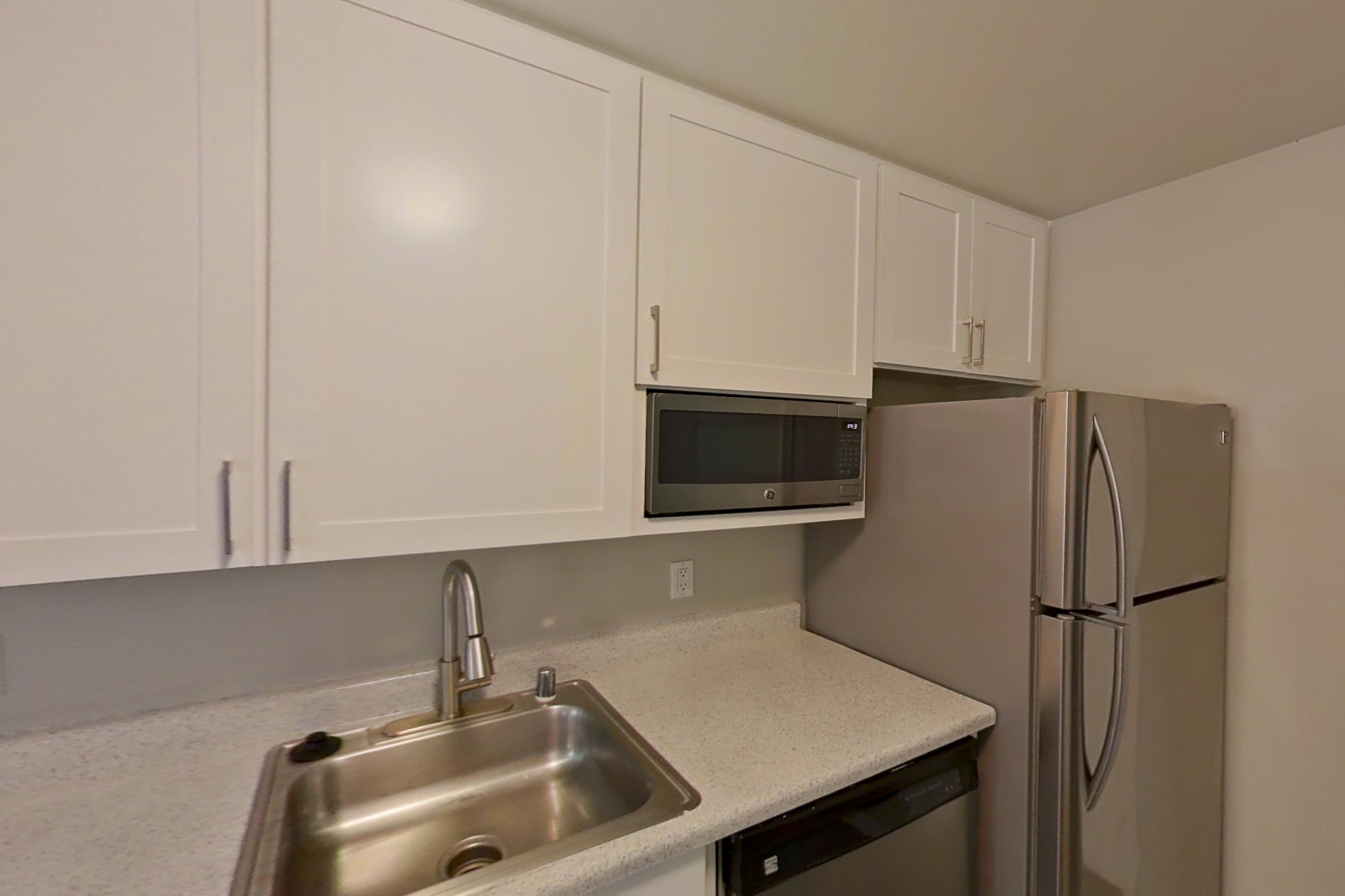 Kitchen with dishwasher, electric range, light countertops, light stone countertops, oven/range, refrigerator, and stainless steel appliances, Apartment 21-01 at Avana Rancho Cucamonga