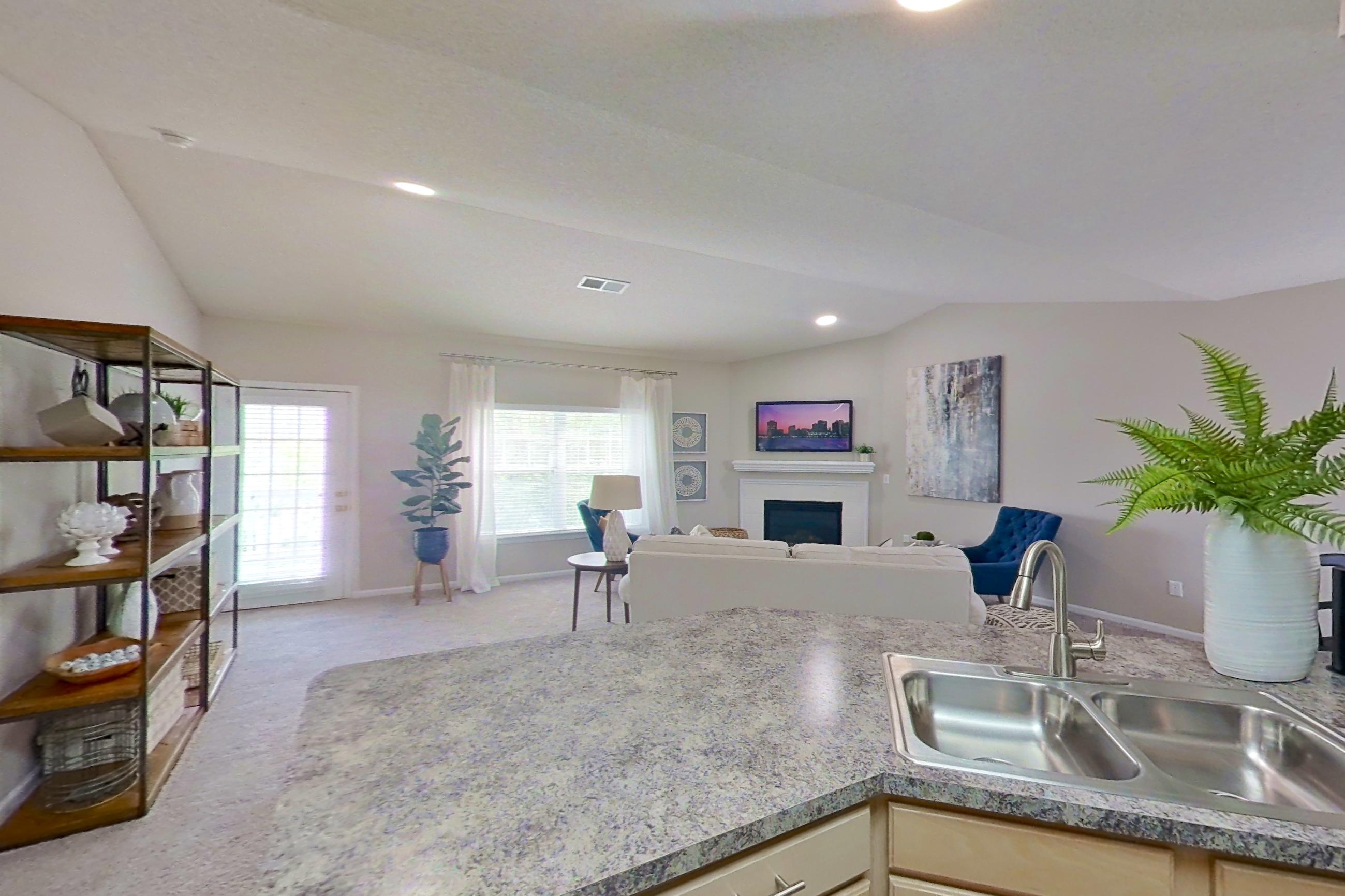 Kitchen with dishwasher, electric range, fireplace, light countertops, light stone countertops, light wood-finish flooring, microwave, oven/range, refrigerator, and stainless steel appliances, Apartment Bradford II at Bradford Pointe