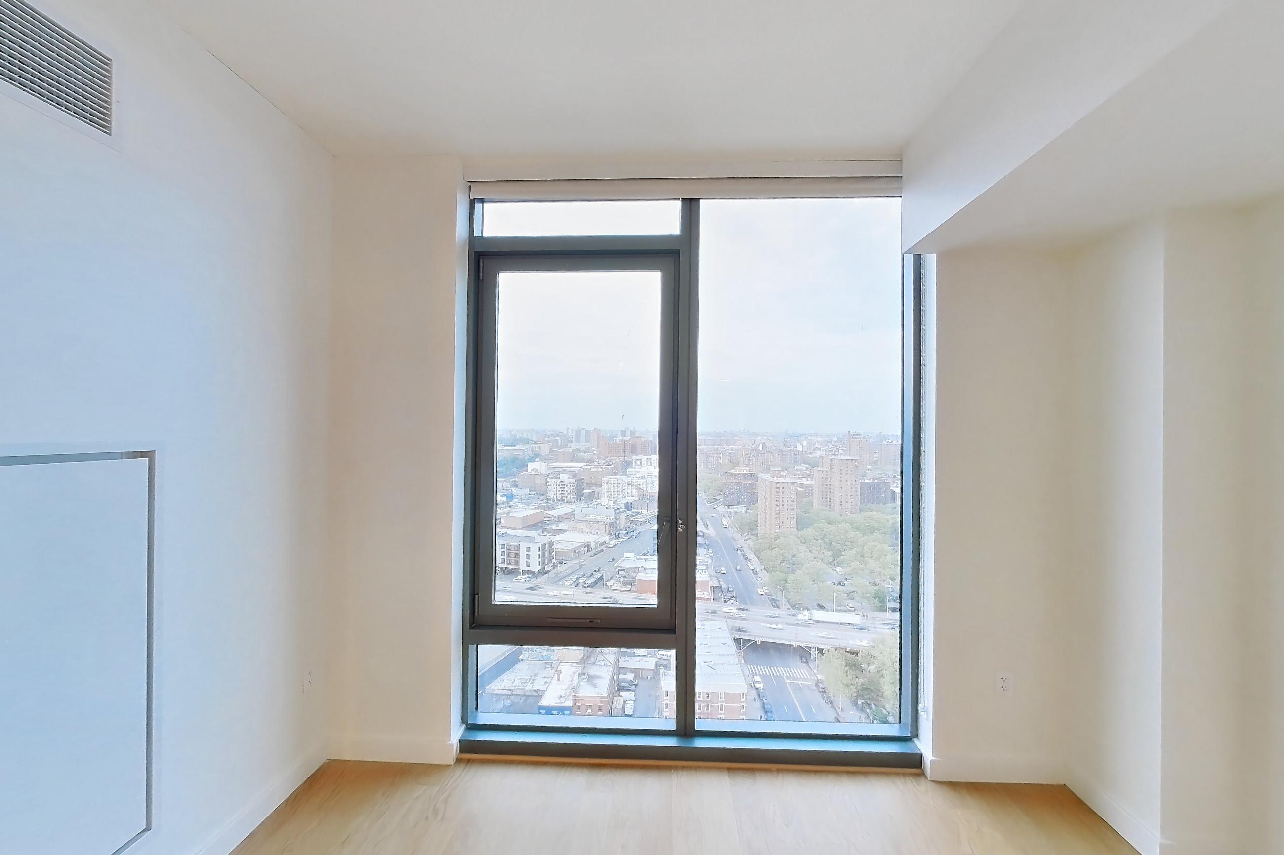 Living space with city view and light wood-finish flooring, Apartment E-2626 at Lincoln at Bankside
