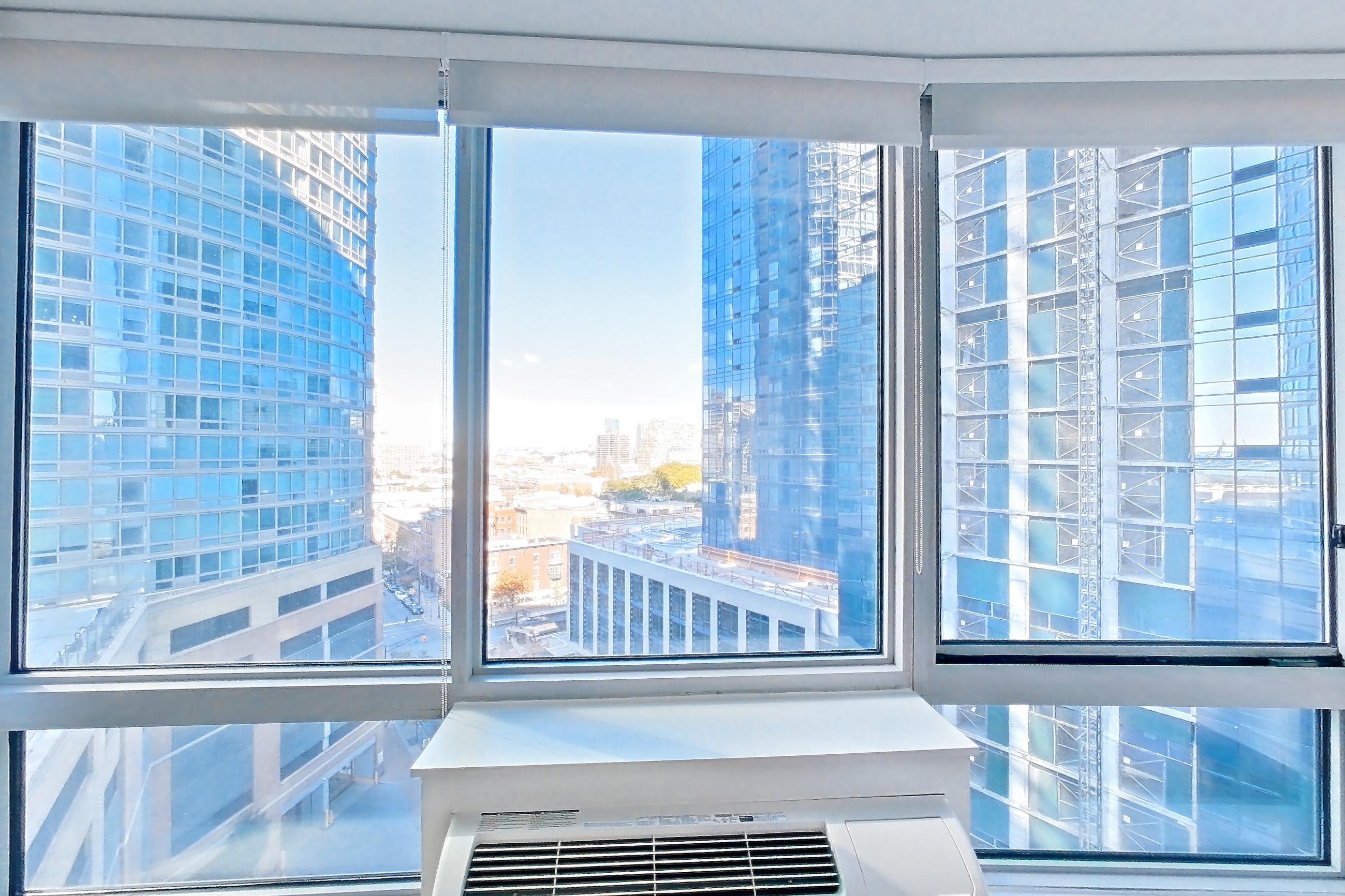 Living room with city view and dark wood-finish flooring, Apartment LT-E1207 at Liberty Towers
