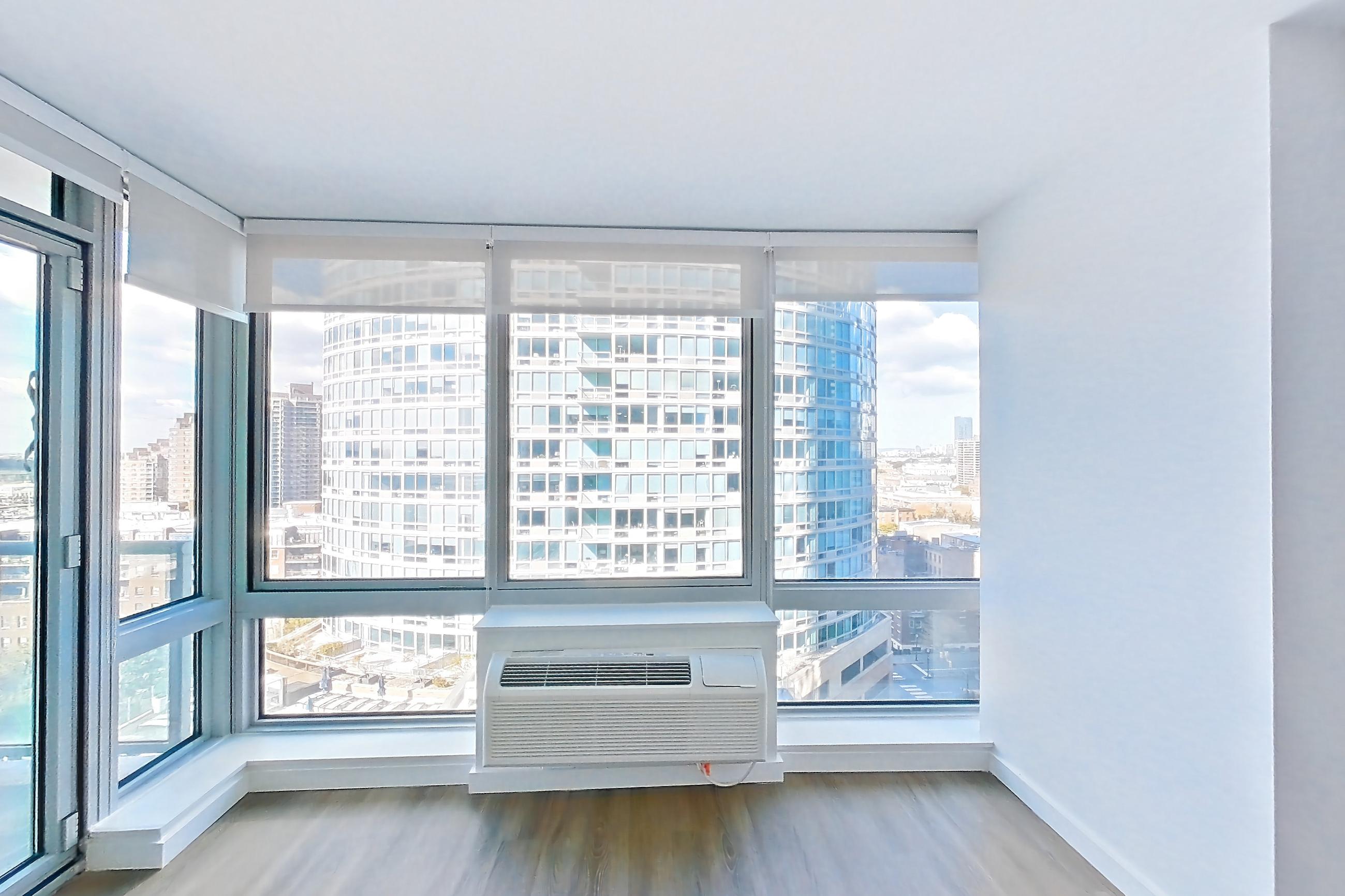 Living room with city view and dark wood-finish flooring, Apartment LT-E1609 at Liberty Towers