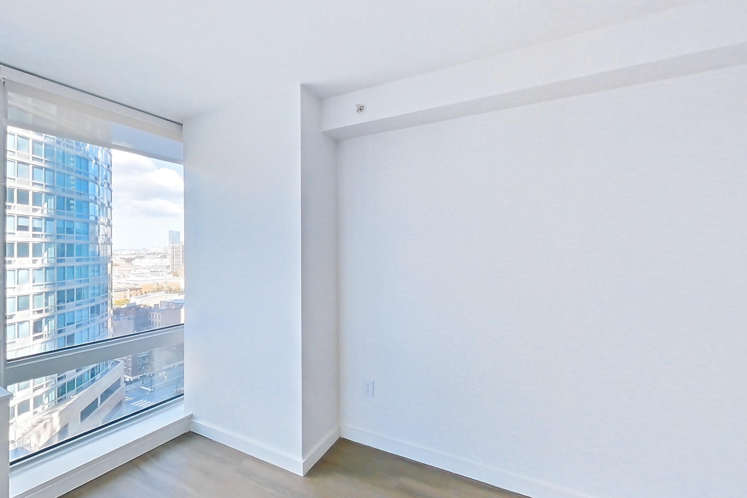 Living room with city view and dark wood-finish flooring, Apartment LT-E1609 at Liberty Towers