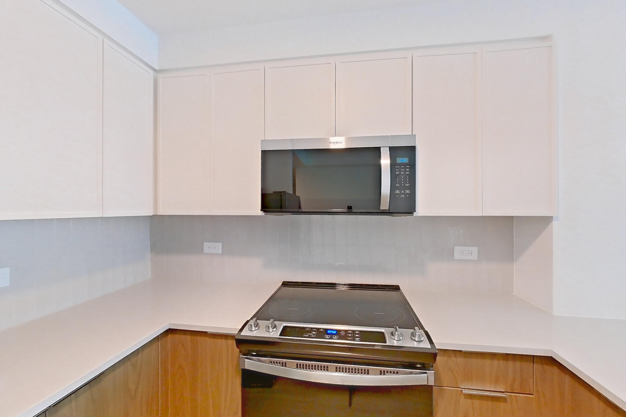 Kitchen with electric range, light stone countertops, light wood-finish flooring, oven/range, and stainless steel appliances, Apartment LT-W2408 at Liberty Towers