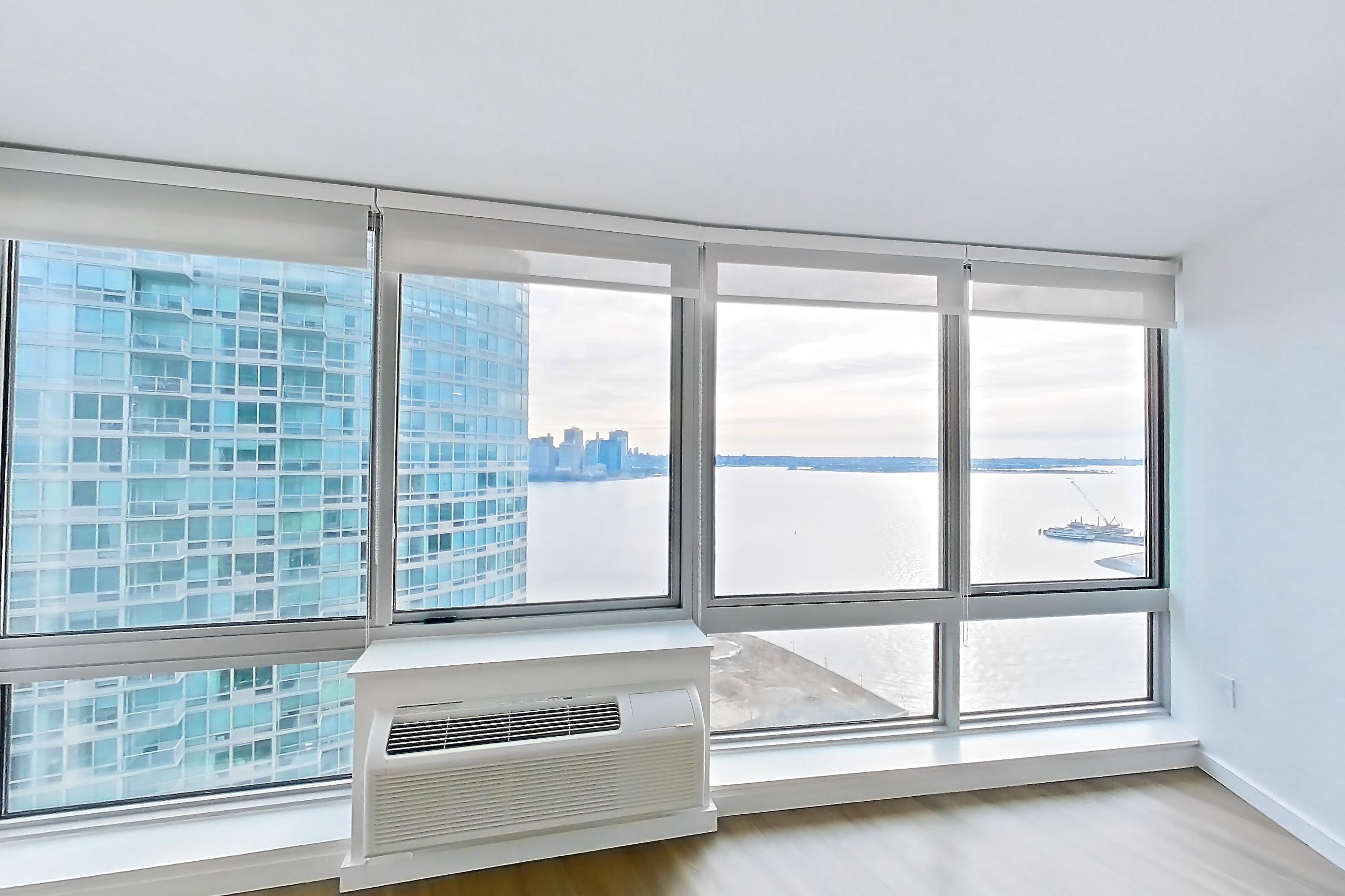 Living room with air conditioning and light wood-finish flooring, Apartment LT-W3011 at Liberty Towers