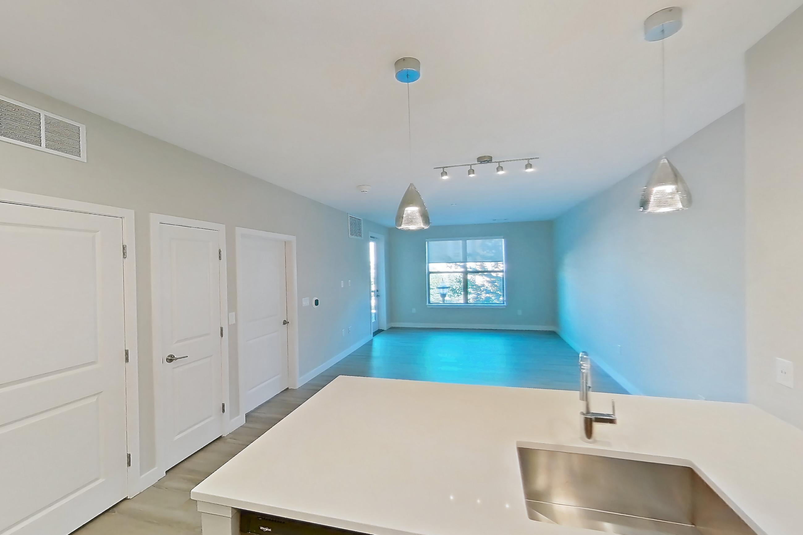 Kitchen with dishwasher, electric range, light countertops, light wood-finish flooring, and stainless steel appliances, Apartment EM-7208 at The Emery at Overlook Ridge