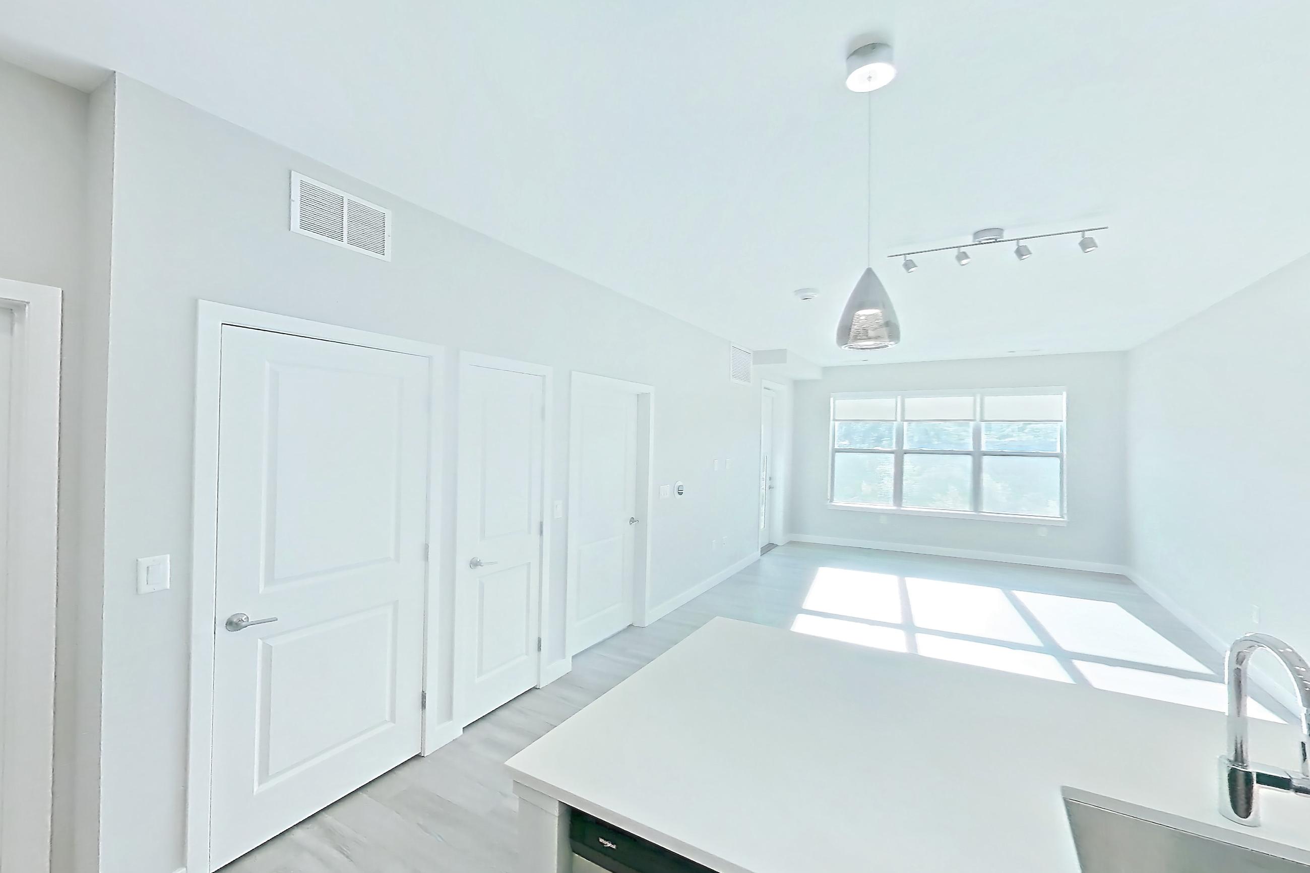 Kitchen with dishwasher, electric range, light countertops, light stone countertops, light wood-finish flooring, microwave, oven/range, and stainless steel appliances, Apartment EM-7513 at The Emery at Overlook Ridge