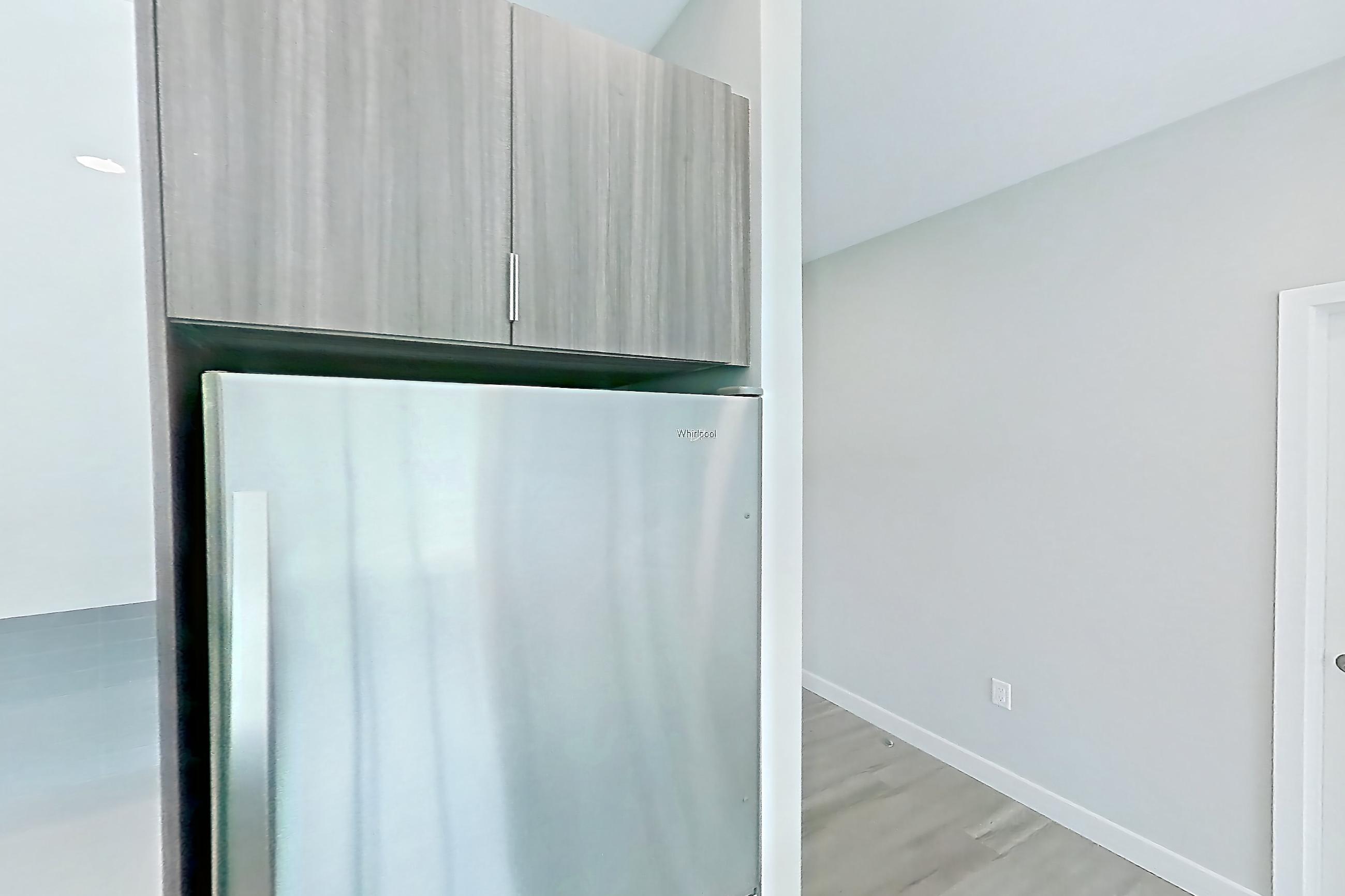 Kitchen with dishwasher, electric range, light countertops, light stone countertops, light wood-finish flooring, microwave, oven/range, and stainless steel appliances, Apartment EM-7513 at The Emery at Overlook Ridge