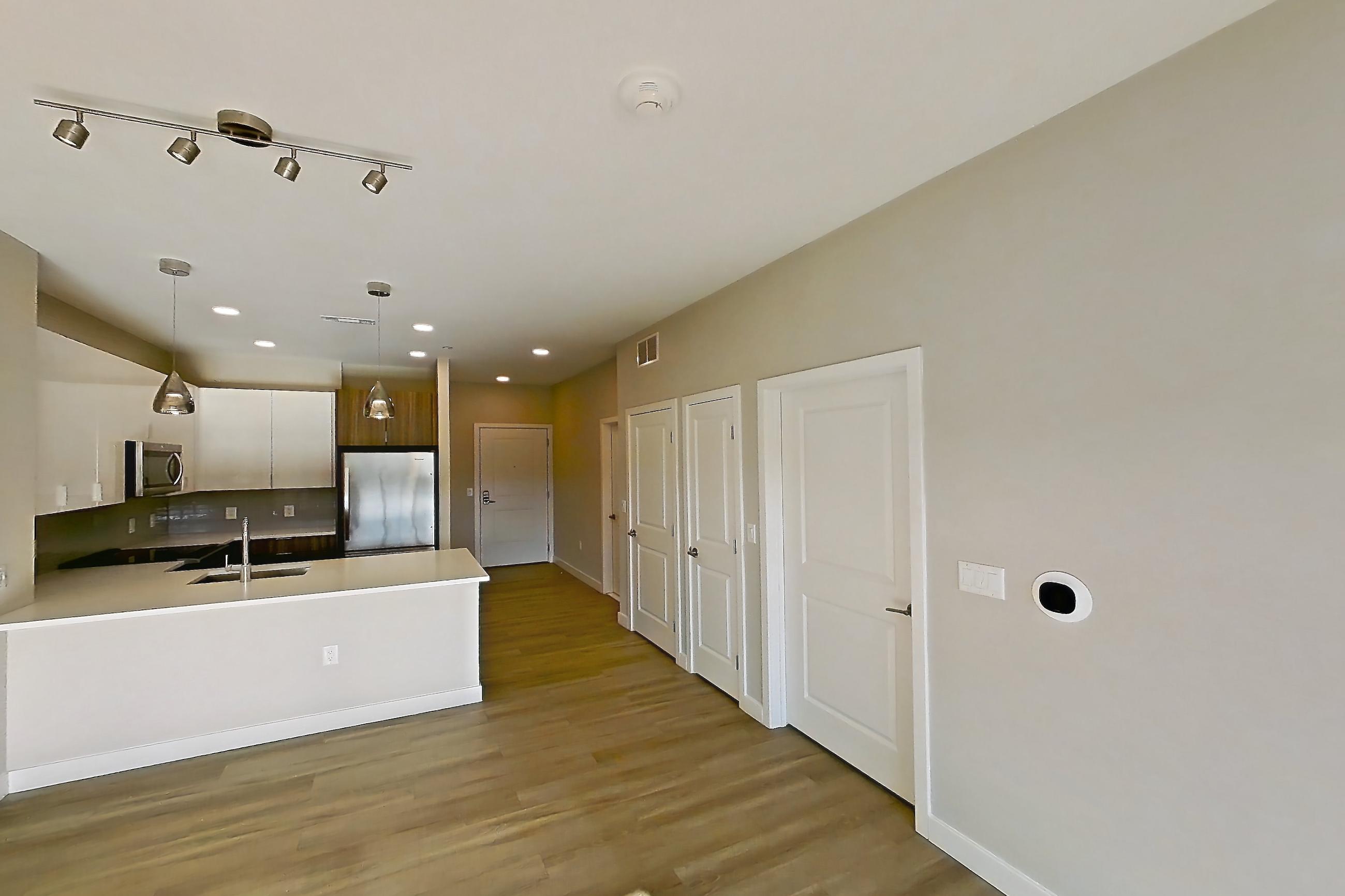 Living room with dark wood-finish flooring and light countertops, Apartment EM-7513 at The Emery at Overlook Ridge