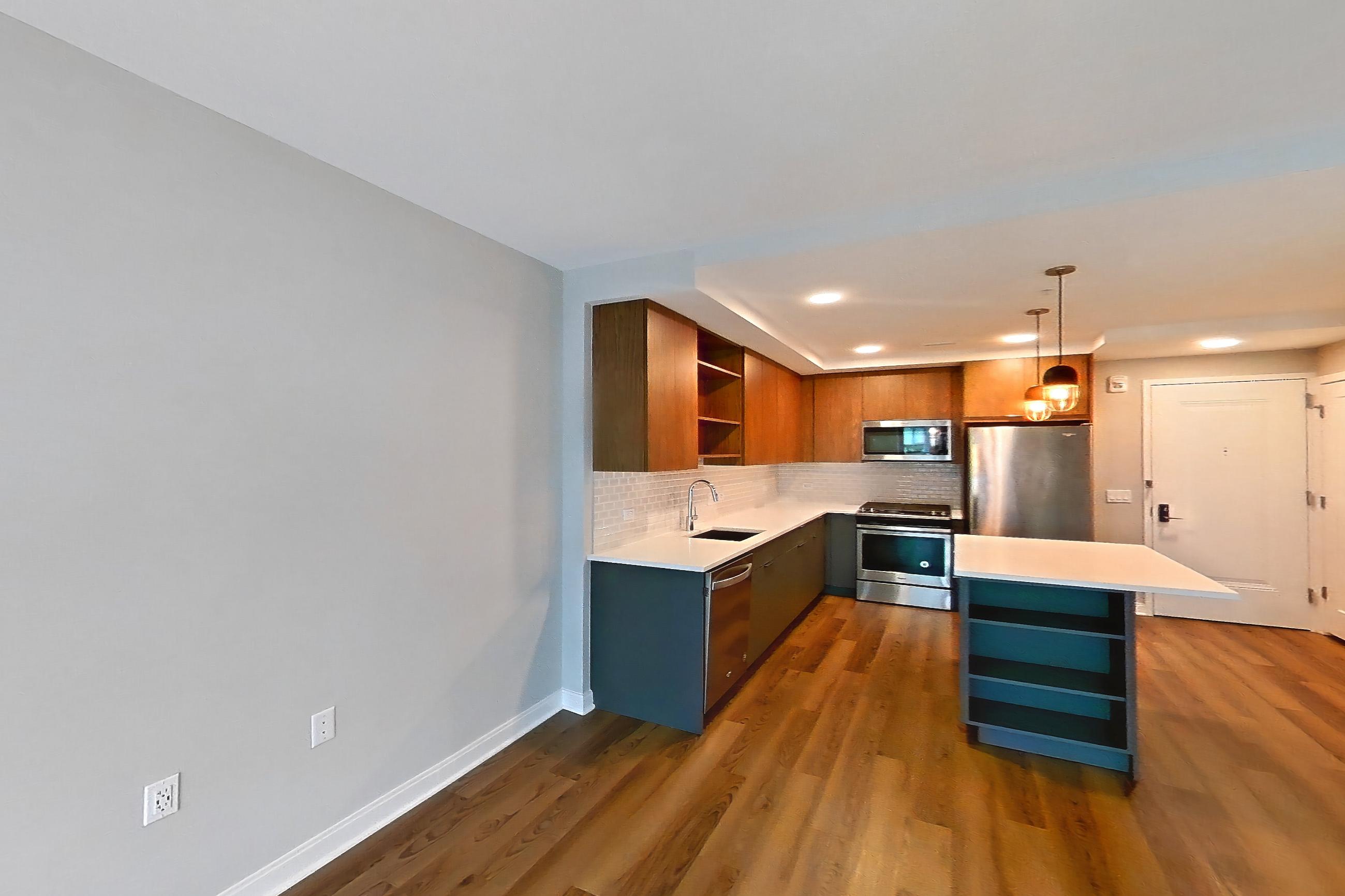 Living room with dark wood-finish flooring, dishwasher, light countertops, light wood-finish flooring, oven/range, refrigerator, and stainless steel appliances, Apartment RH9-0610 at RiverHouse9