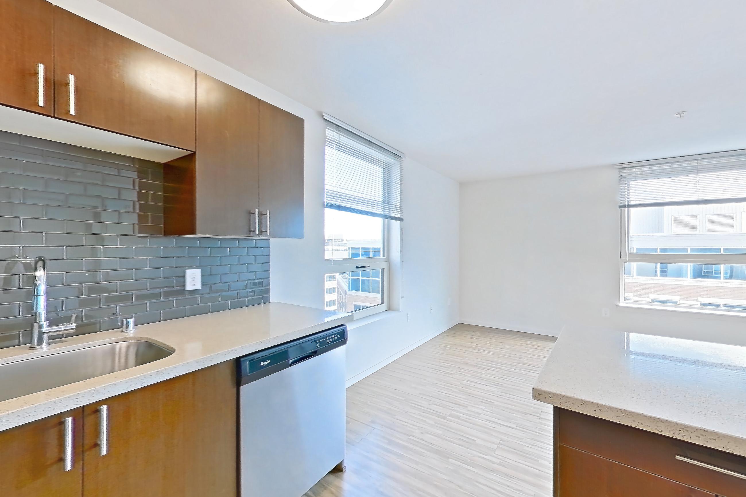 Kitchen island with dishwasher, light stone countertops, light wood-finish flooring, refrigerator, and stainless steel appliances, Apartment L600 at Union SLU
