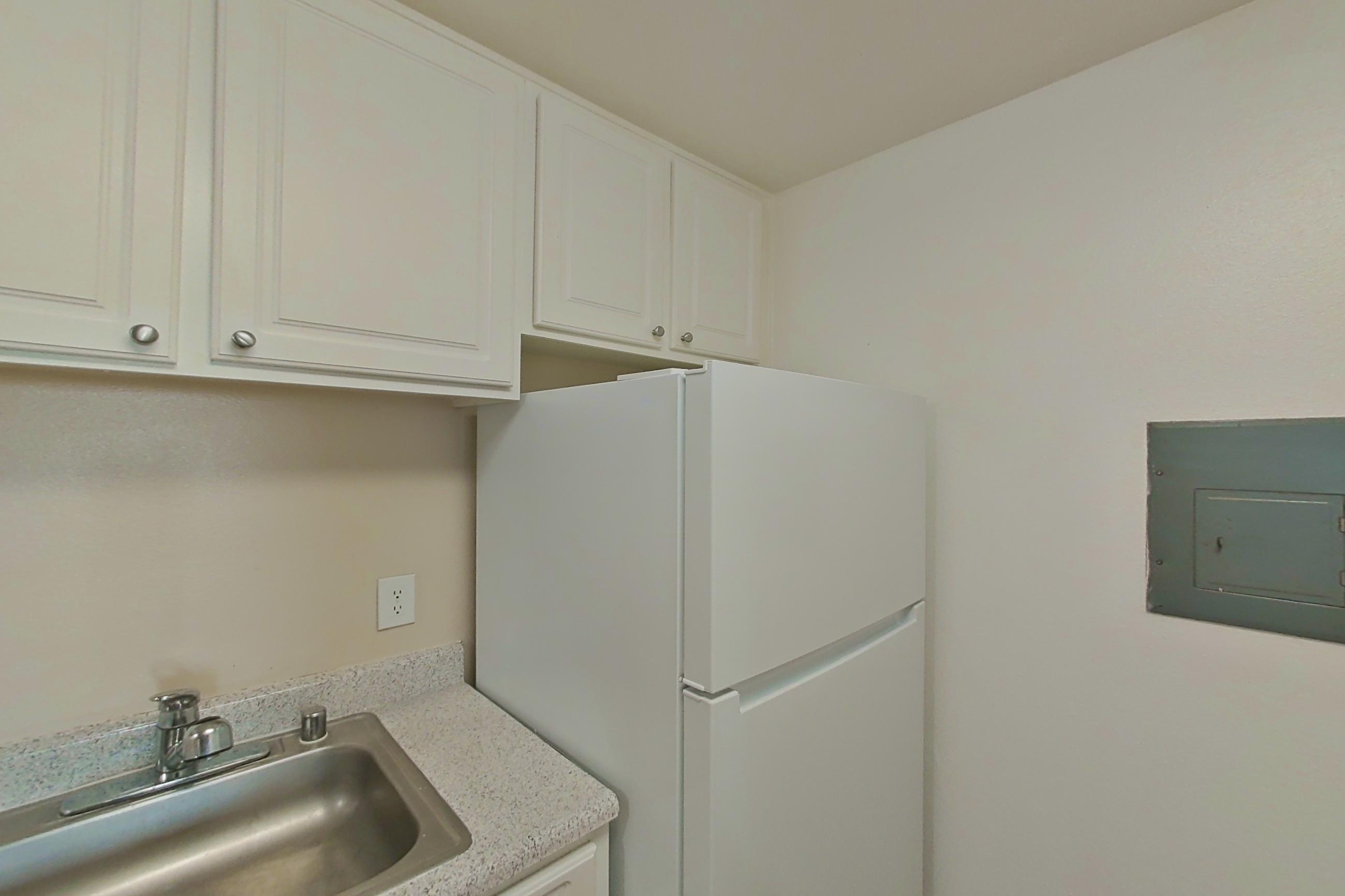 Kitchen with dishwasher, electric range, light countertops, light wood-finish flooring, oven/range, refrigerator, and white appliances, Apartment 16-16 at Avana Rancho Cucamonga