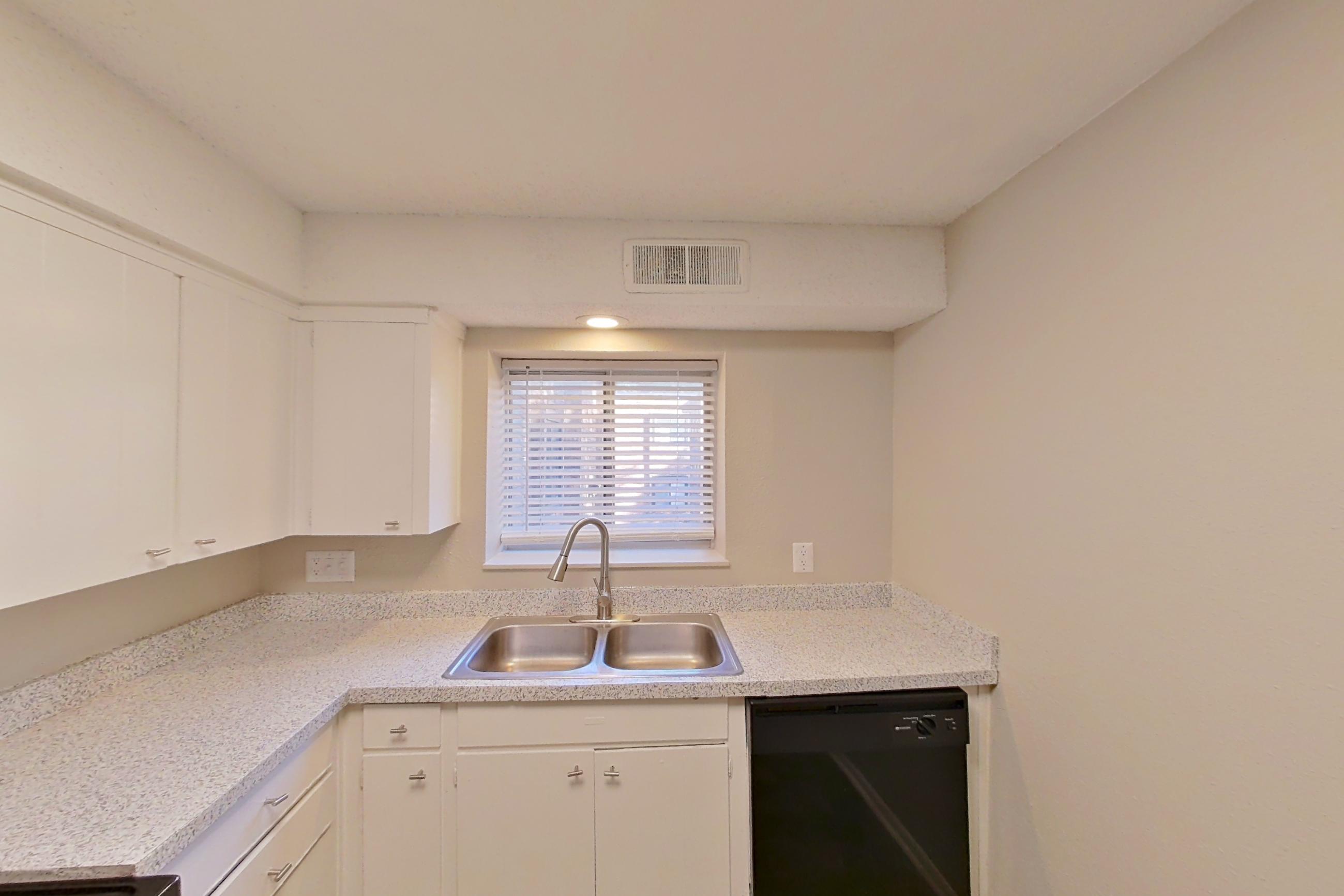 Kitchen with black appliances, dishwasher, electric range, light countertops, light stone countertops, light wood-finish flooring, microwave, oven/range, and refrigerator, Apartment 1426A at The Life at Legacy Fountains