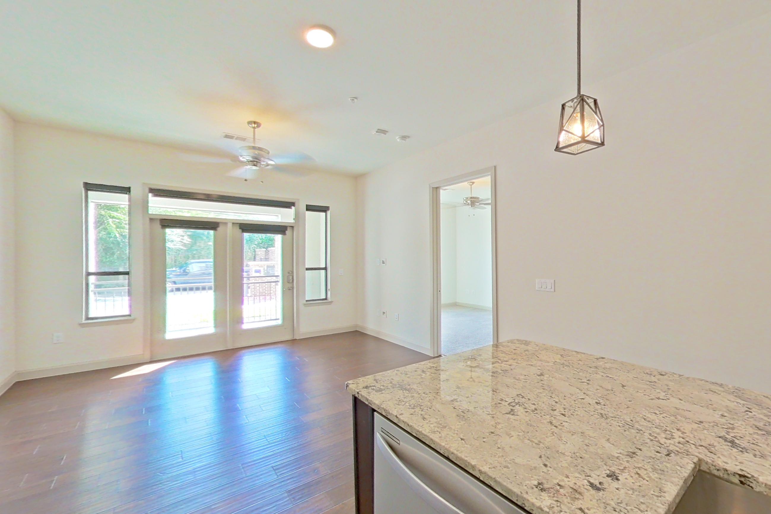 Kitchen with dark wood-finish flooring, dishwasher, gas range, light stone countertops, oven/range, refrigerator, stainless steel appliances, water & ice dispenser, and wood-finish flooring, Apartment 139 at Sinclair