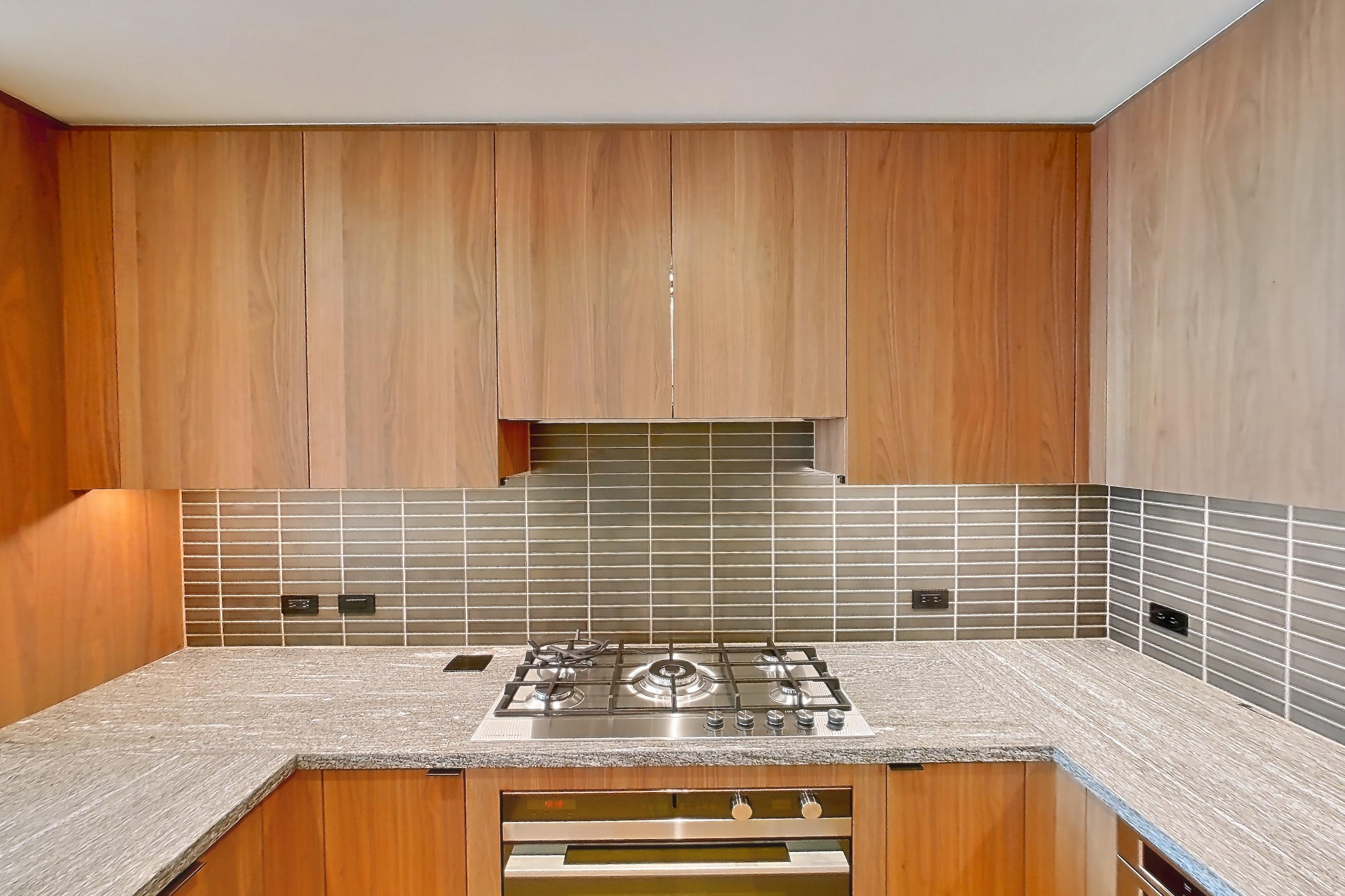 Kitchen with cooktop, gas cooktop, light stone countertops, oven/range, and stainless steel appliances, Apartment B-5202 at Beaudry