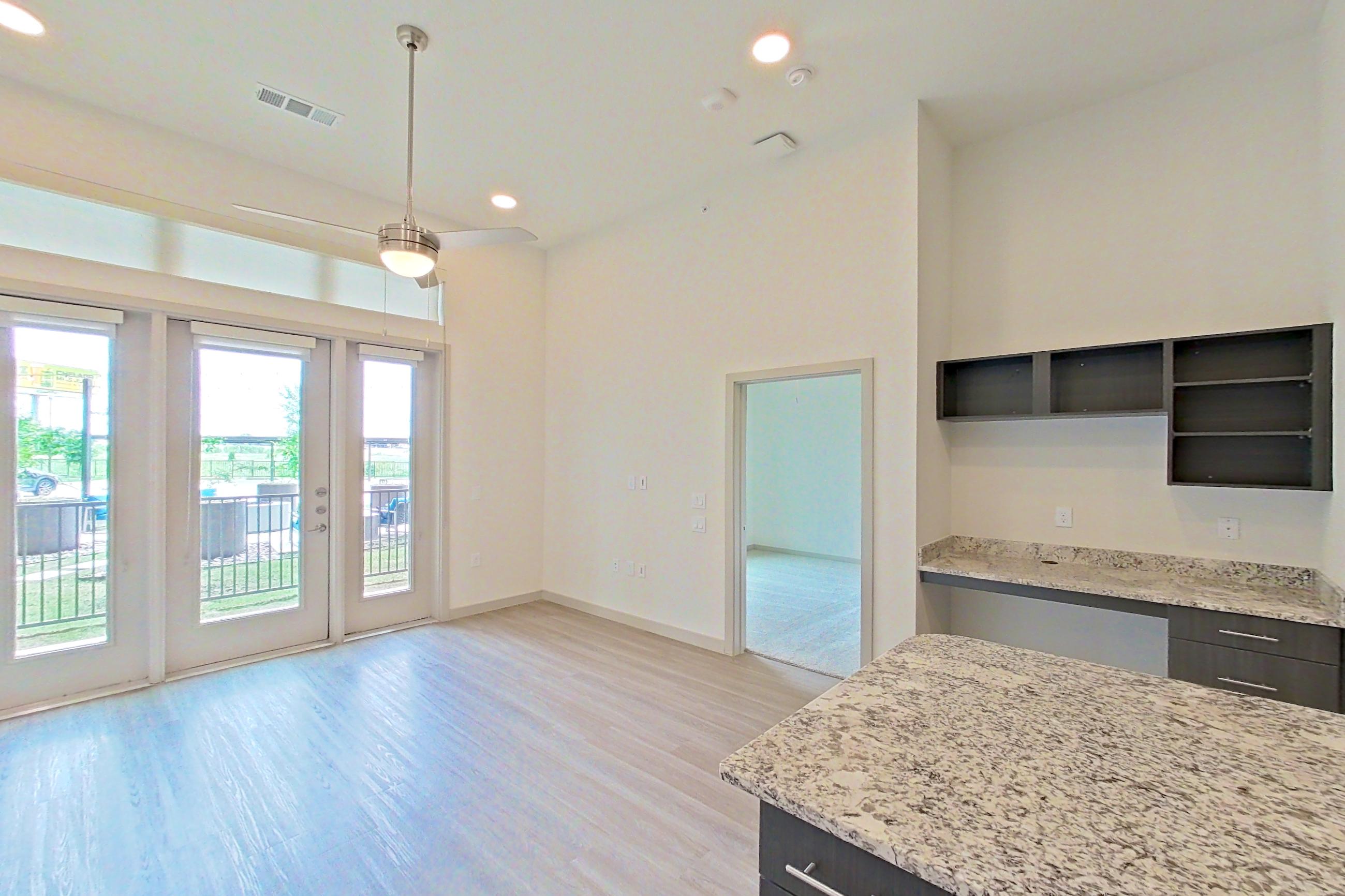 Kitchen with dishwasher, electric range, light stone countertops, light wood-finish flooring, microwave, oven/range, and stainless steel appliances, Apartment 2162 at Merit Lewisville