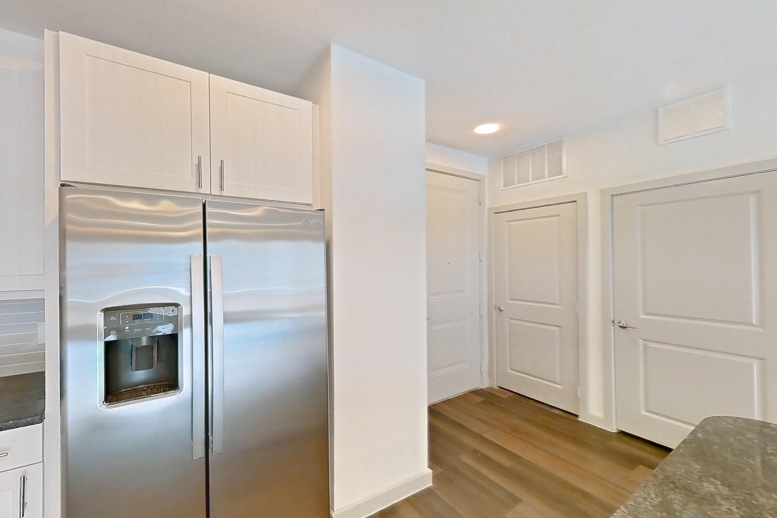 Kitchen with dark stone countertops, dark wood-finish flooring, dishwasher, electric range, microwave, oven/range, refrigerator, stainless steel appliances, and wood-finish flooring, Apartment 2230 at Merit Lewisville