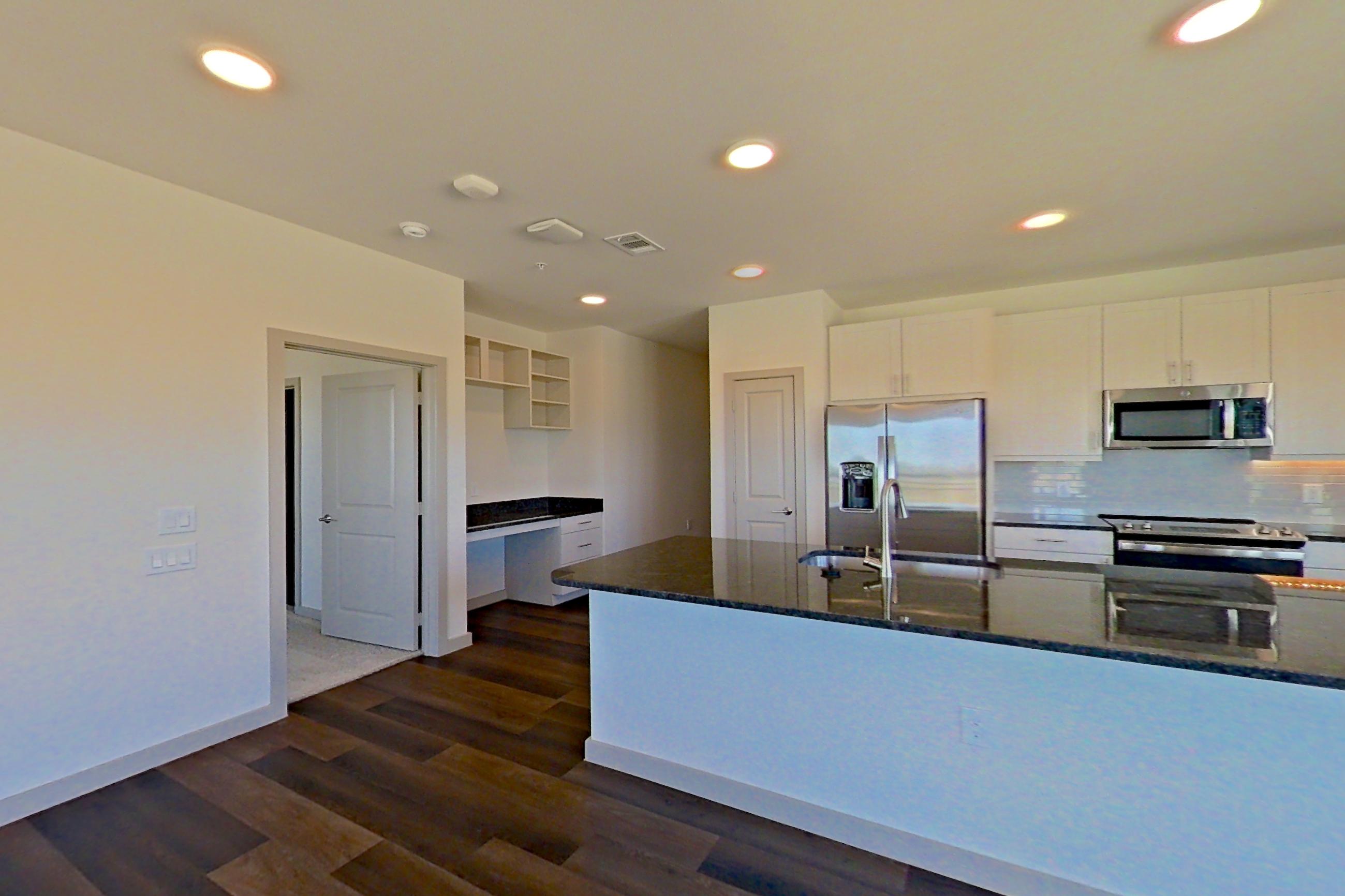 Living room with dark stone countertops, dark wood-finish flooring, electric range, kitchen island, oven/range, refrigerator, and stainless steel appliances, Apartment 1201 at Merit Lewisville