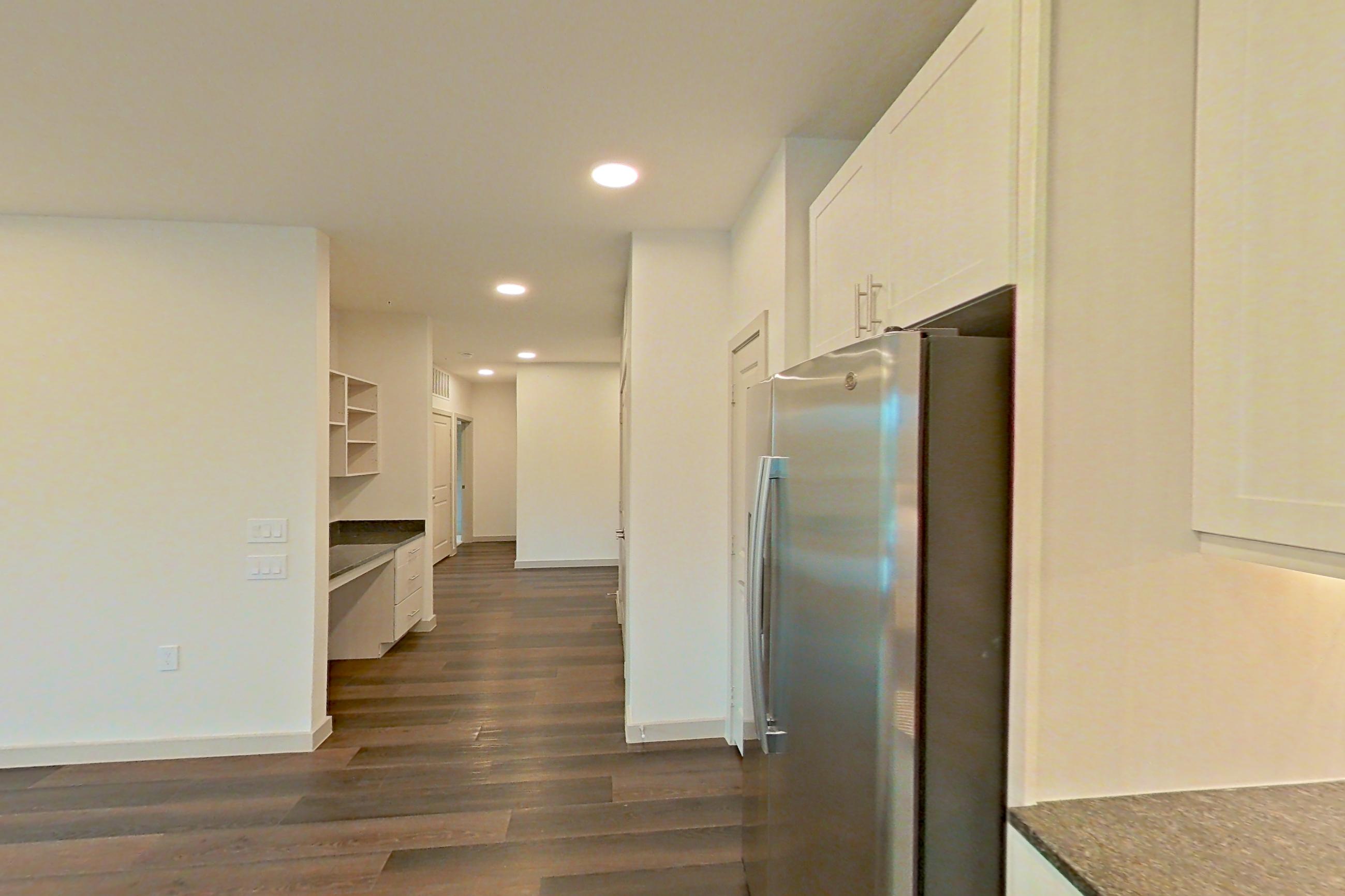 Kitchen with dark stone countertops, dark wood-finish flooring, dishwasher, electric range, microwave, oven/range, refrigerator, and stainless steel appliances, Apartment 2233 at Merit Lewisville
