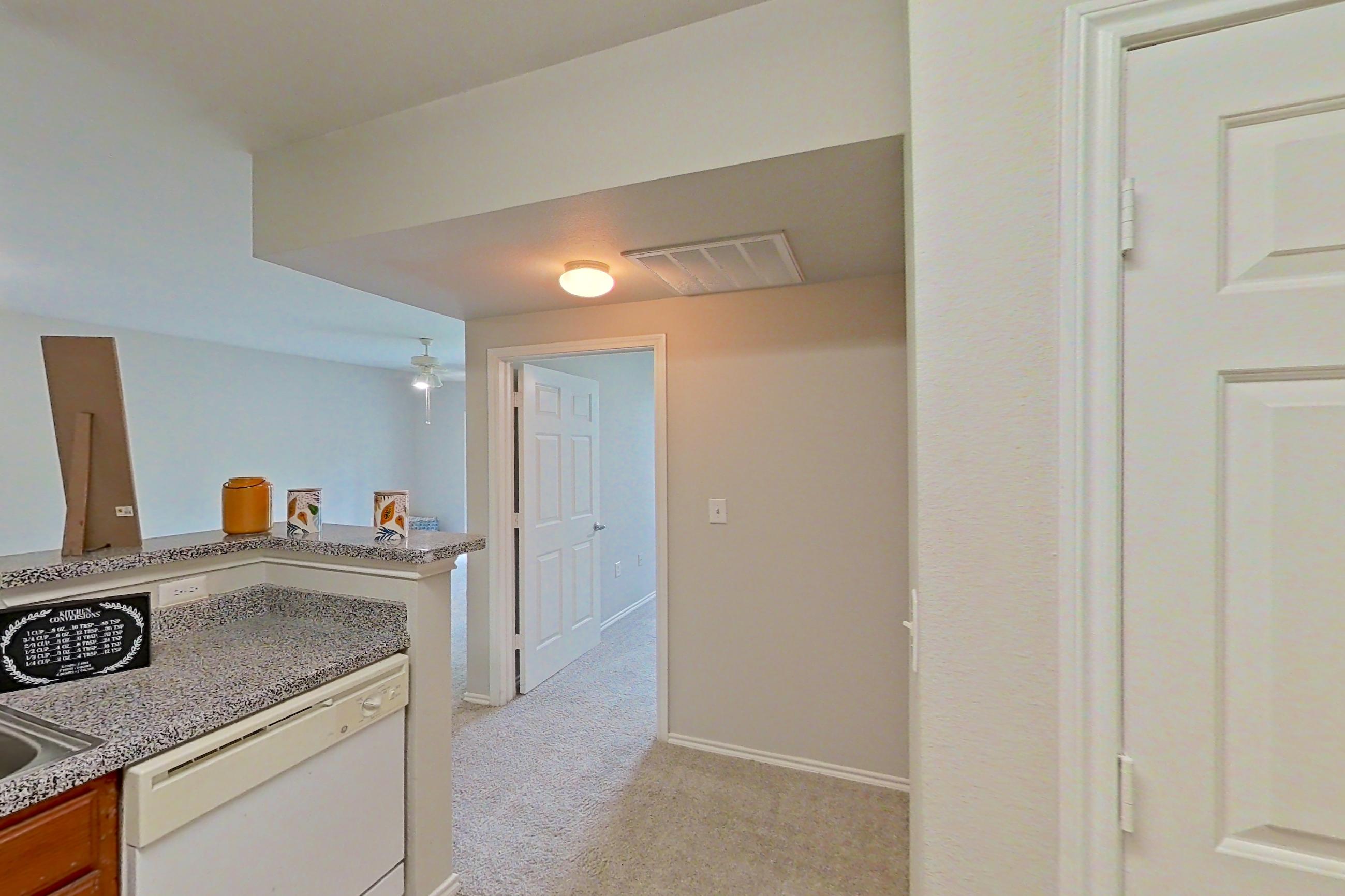 Kitchen with dishwasher, electric range, light carpet, light countertops, light tile flooring, microwave, oven/range, and white appliances, Apartment 1204 at The Life at Brighton Estates
