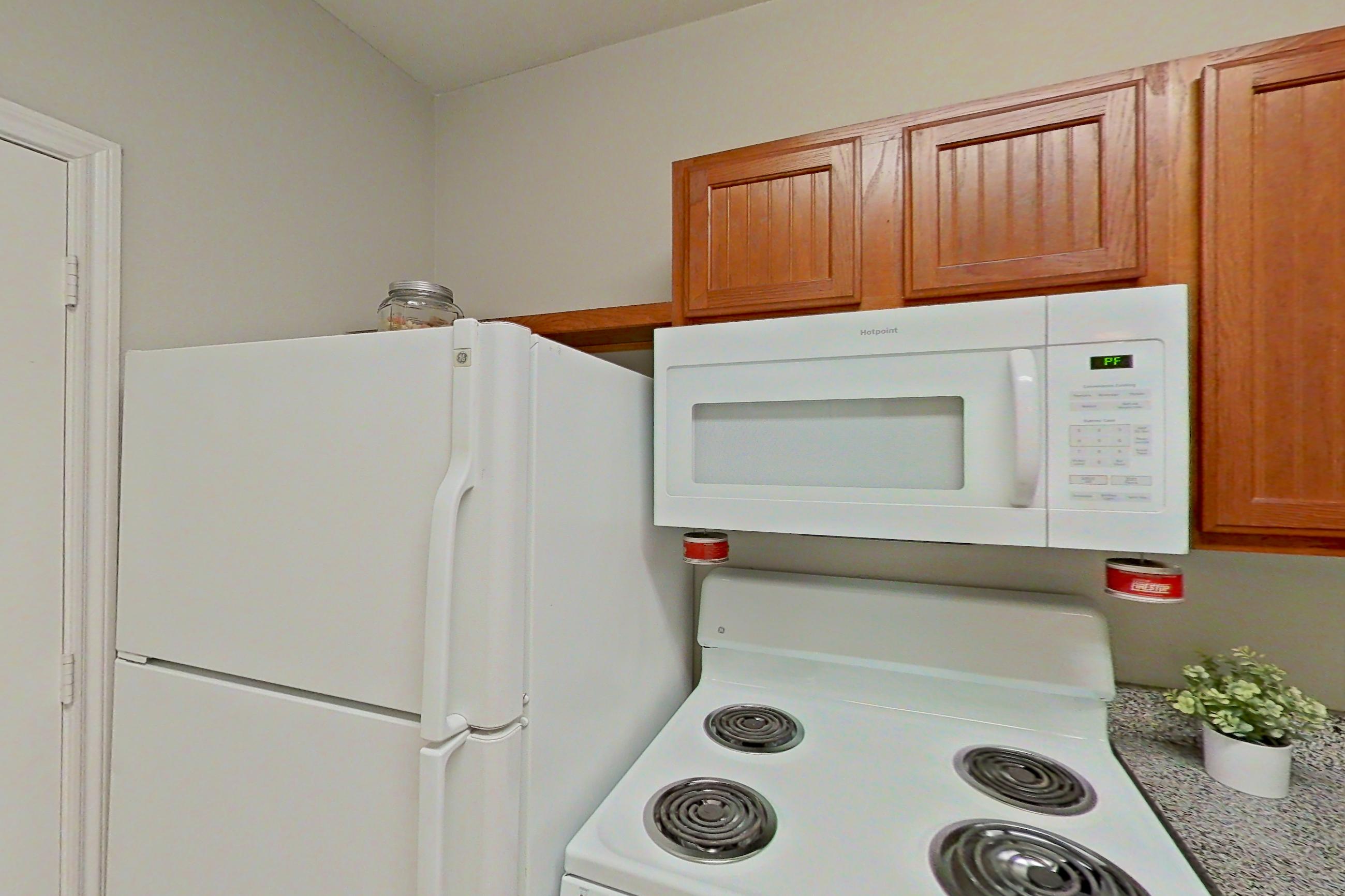 Kitchen with dishwasher, electric range, light carpet, light countertops, light tile flooring, microwave, oven/range, and white appliances, Apartment 1204 at The Life at Brighton Estates