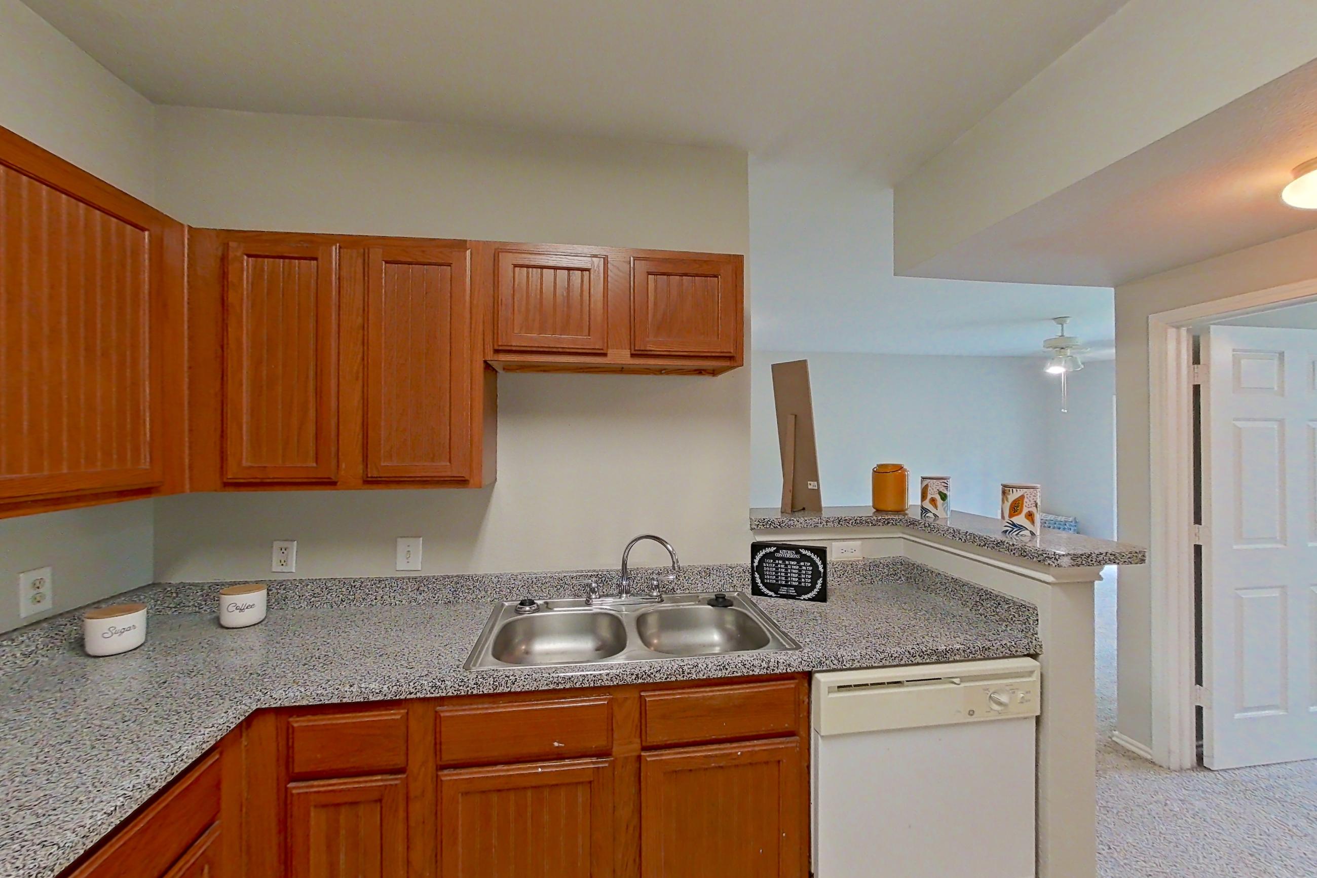 Kitchen with dishwasher, electric range, light carpet, light countertops, light tile flooring, microwave, oven/range, and white appliances, Apartment 1204 at The Life at Brighton Estates