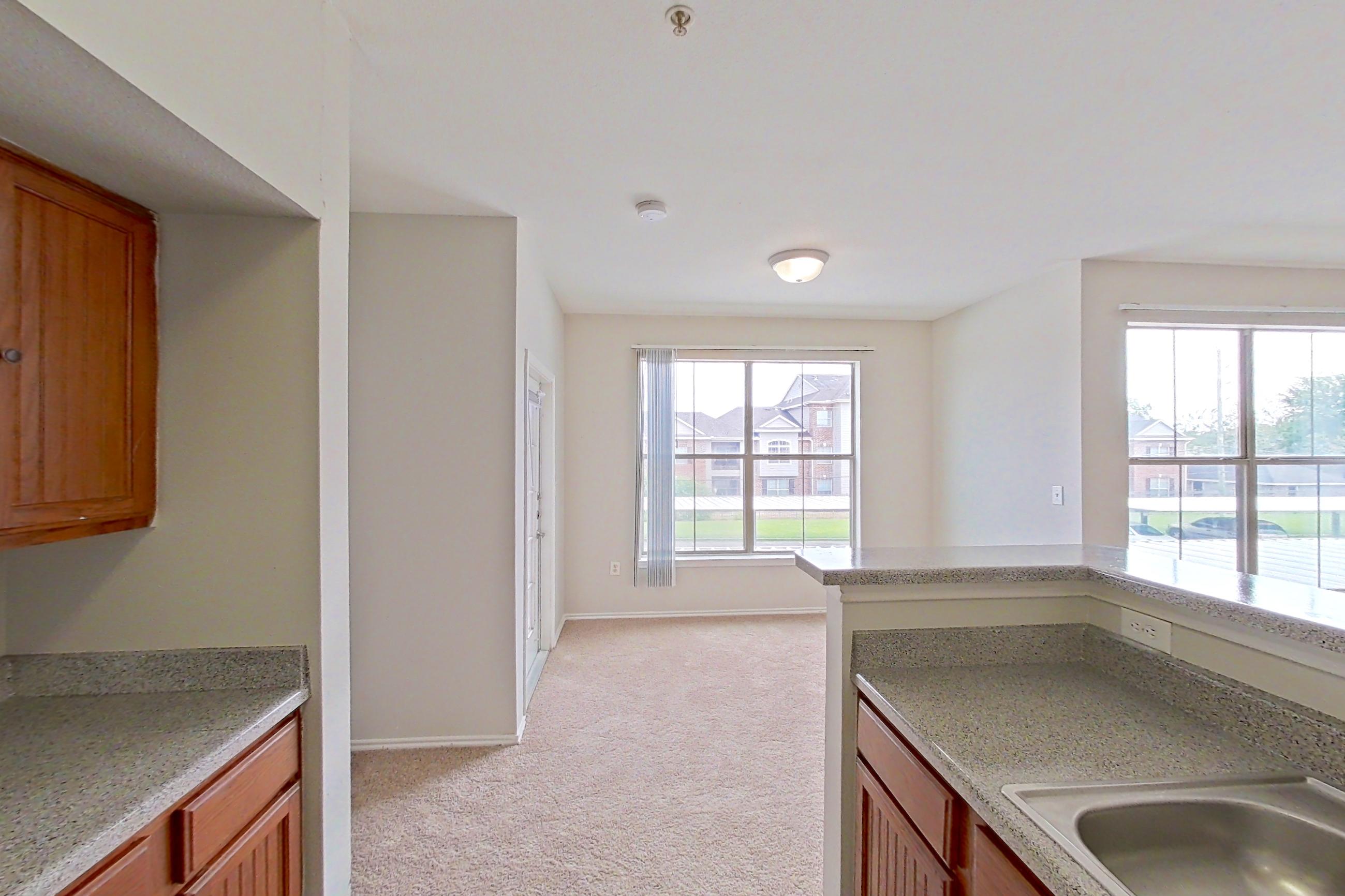 Kitchen with dishwasher, electric range, light carpet, light countertops, light stone countertops, light wood-finish flooring, microwave, oven/range, refrigerator, and white appliances, Apartment 1205 at The Life at Brighton Estates