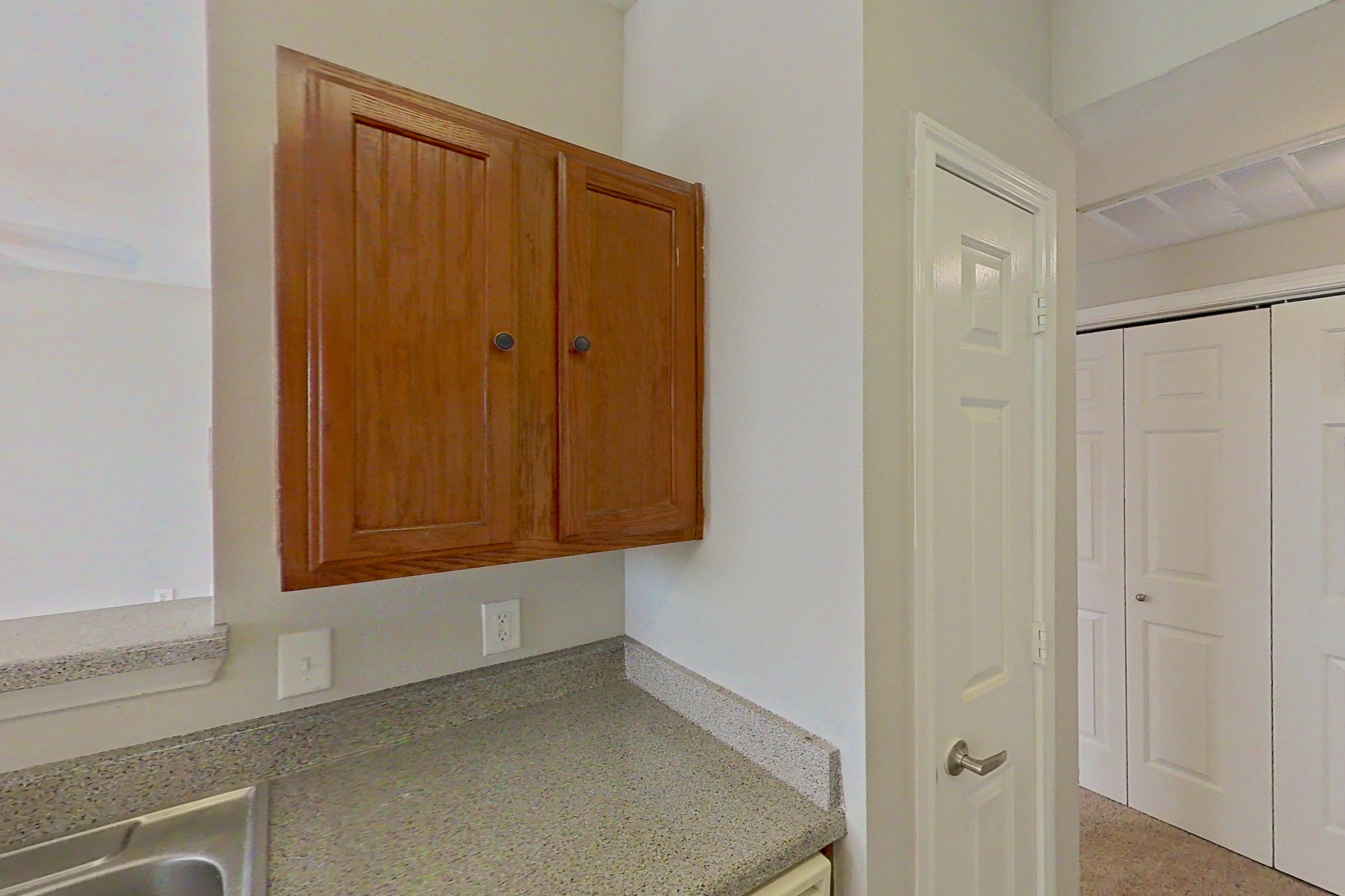 Kitchen with dishwasher, electric range, light carpet, light countertops, light stone countertops, light wood-finish flooring, microwave, oven/range, refrigerator, and white appliances, Apartment 1205 at The Life at Brighton Estates
