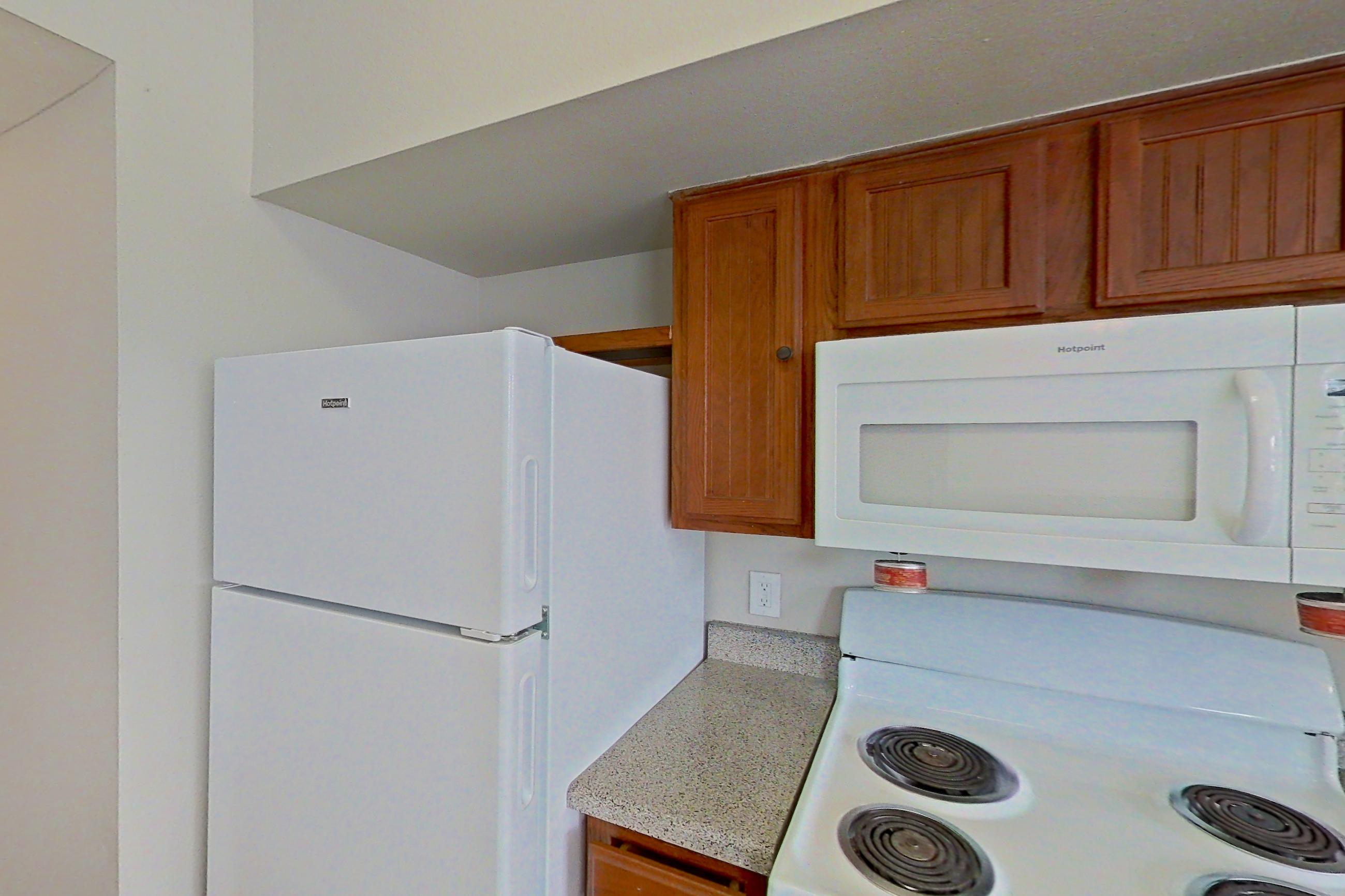 Kitchen with dishwasher, electric range, light carpet, light countertops, light stone countertops, light wood-finish flooring, microwave, oven/range, refrigerator, and white appliances, Apartment 1205 at The Life at Brighton Estates