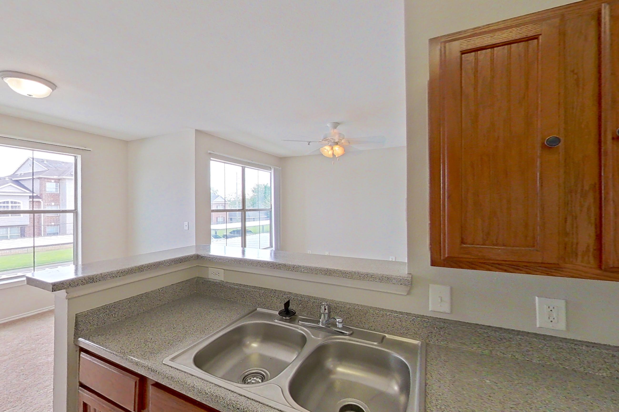 Kitchen with dishwasher, electric range, light carpet, light countertops, light stone countertops, light wood-finish flooring, microwave, oven/range, refrigerator, and white appliances, Apartment 1205 at The Life at Brighton Estates