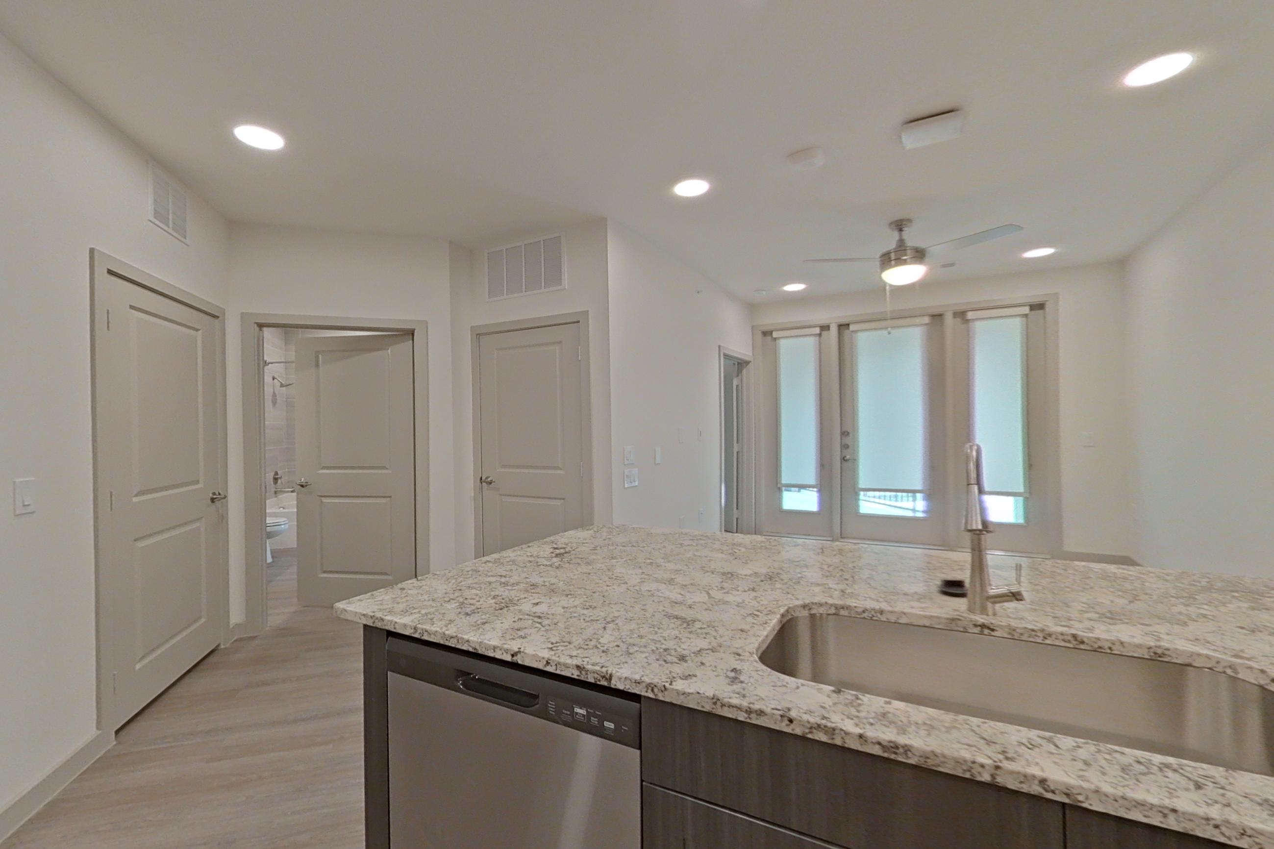 Kitchen with dishwasher, electric range, light stone countertops, light wood-finish flooring, microwave, oven/range, refrigerator, stainless steel appliances, and water & ice dispenser, Apartment 1302 at Merit Lewisville