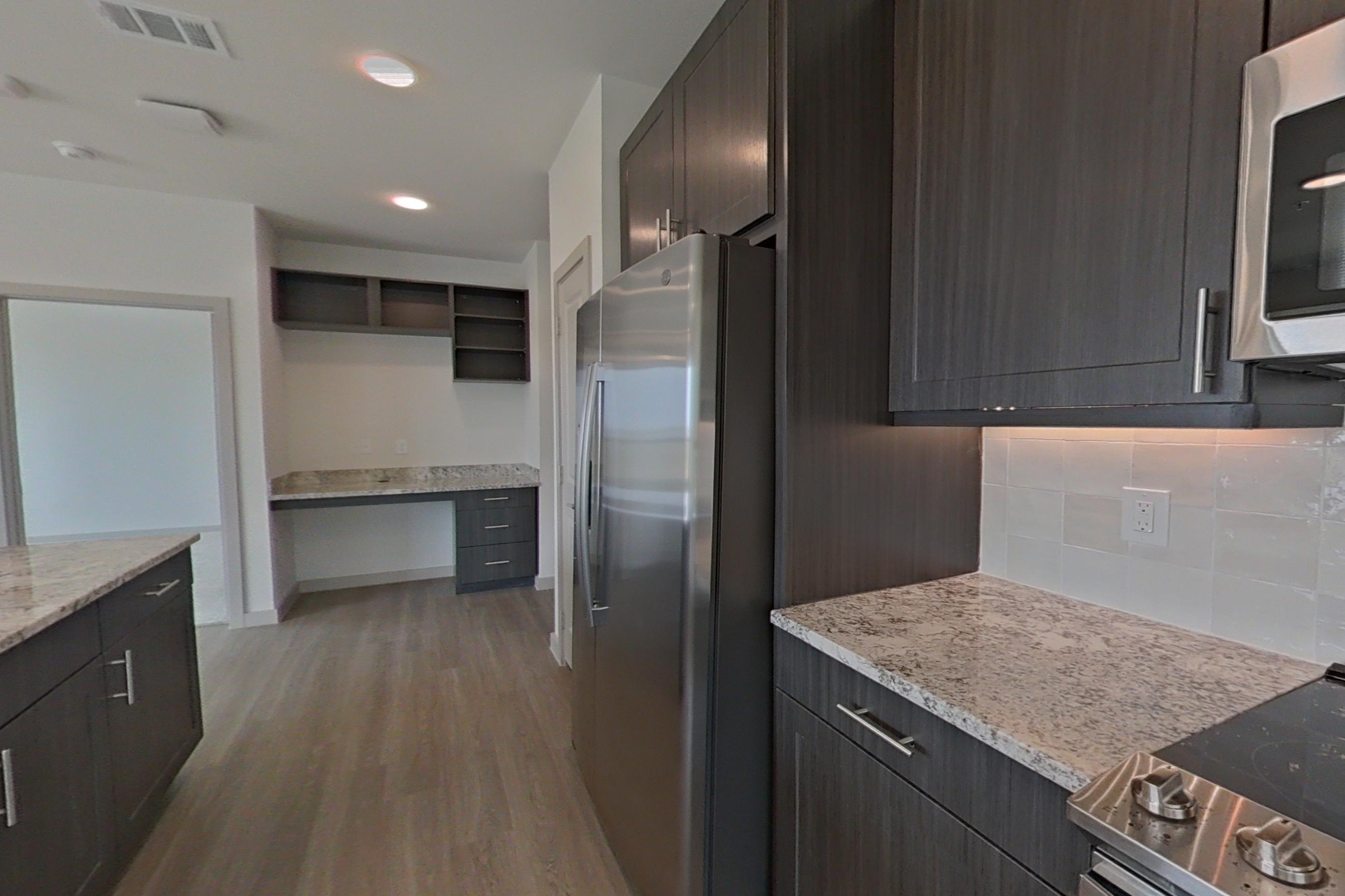 Kitchen with dishwasher, electric range, light stone countertops, light wood-finish flooring, microwave, oven/range, refrigerator, and stainless steel appliances, Apartment 1305 at Merit Lewisville