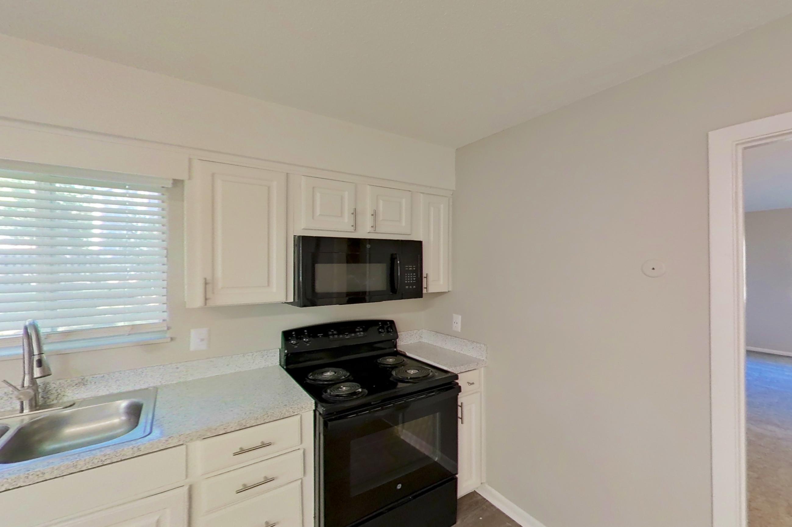Kitchen with black appliances, dishwasher, electric range, light stone countertops, light wood-finish flooring, oven/range, and refrigerator, Apartment 1707 at The Life at Legacy Fountains
