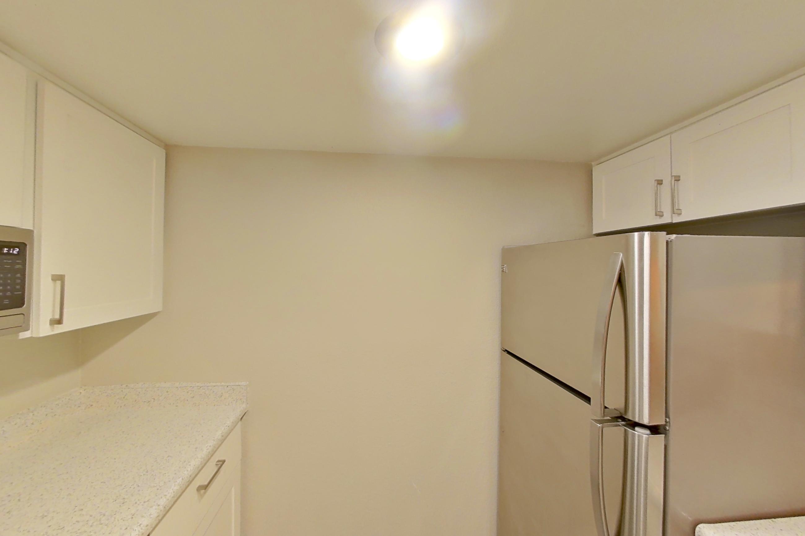 Kitchen with dishwasher, electric range, light stone countertops, light wood-finish flooring, oven/range, refrigerator, stainless steel appliances, and white appliances, Apartment 19 at Avana Rancho Cucamonga
