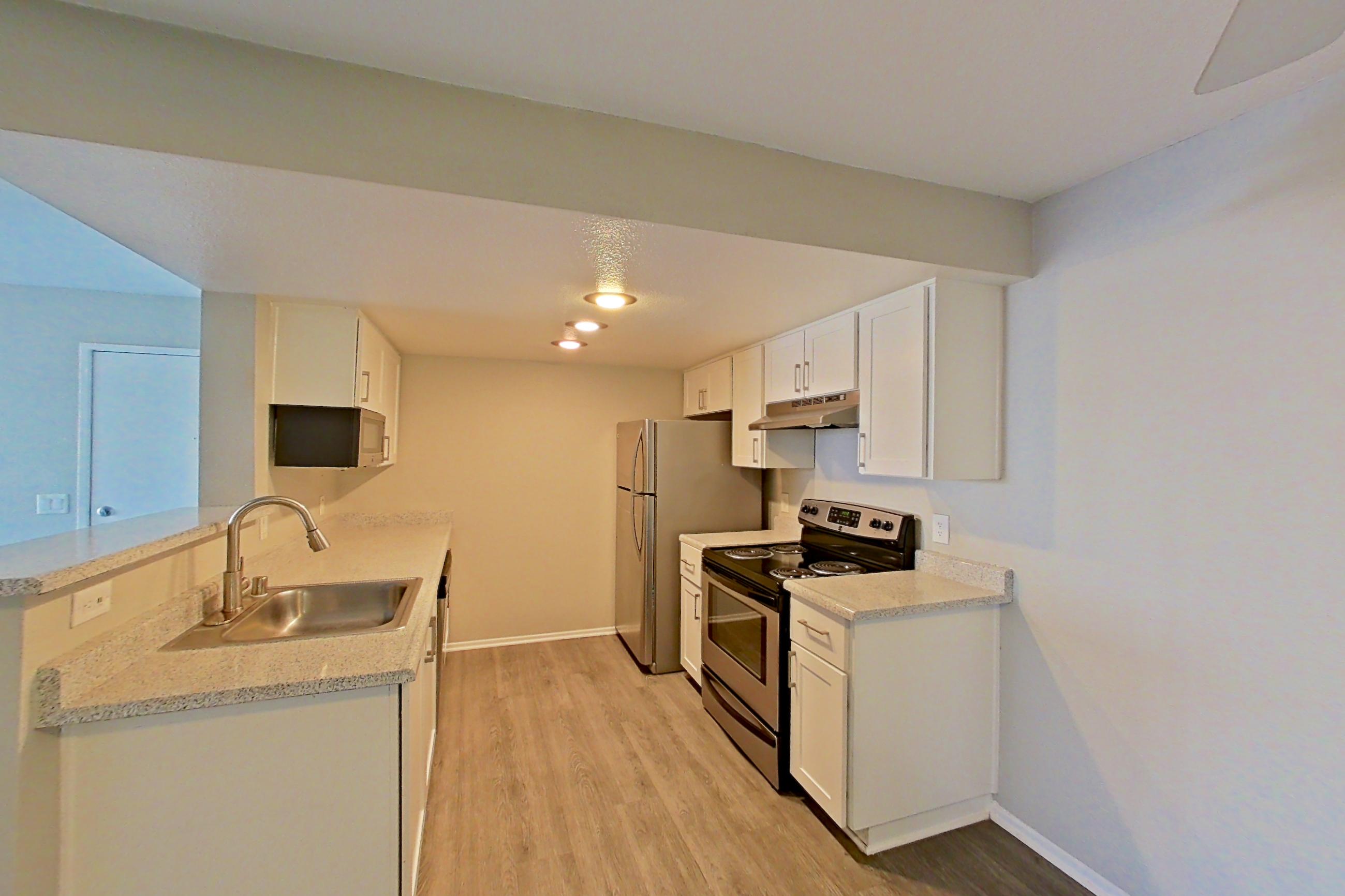 Dining area with dark wood-finish flooring, electric range, light countertops, light wood-finish flooring, oven/range, refrigerator, and stainless steel appliances, Apartment 11 at Avana Rancho Cucamonga