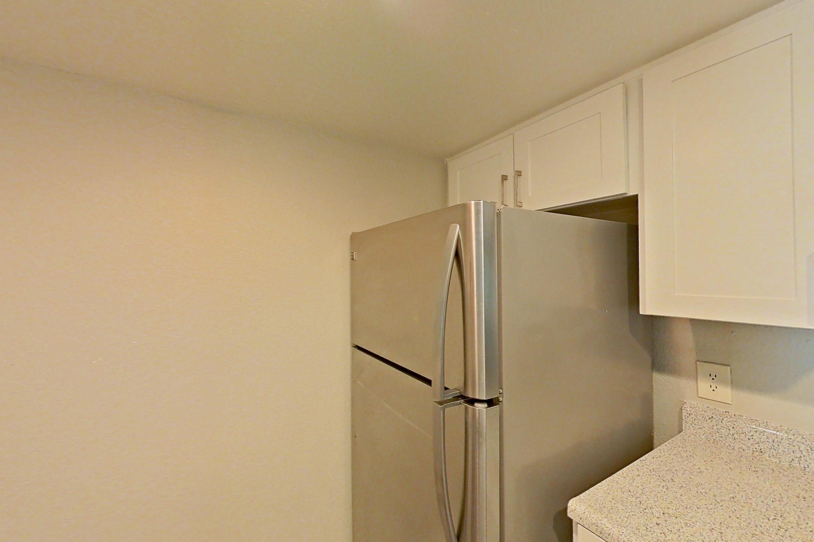 Kitchen with dishwasher, light stone countertops, light wood-finish flooring, microwave, refrigerator, and stainless steel appliances, Apartment 11 at Avana Rancho Cucamonga