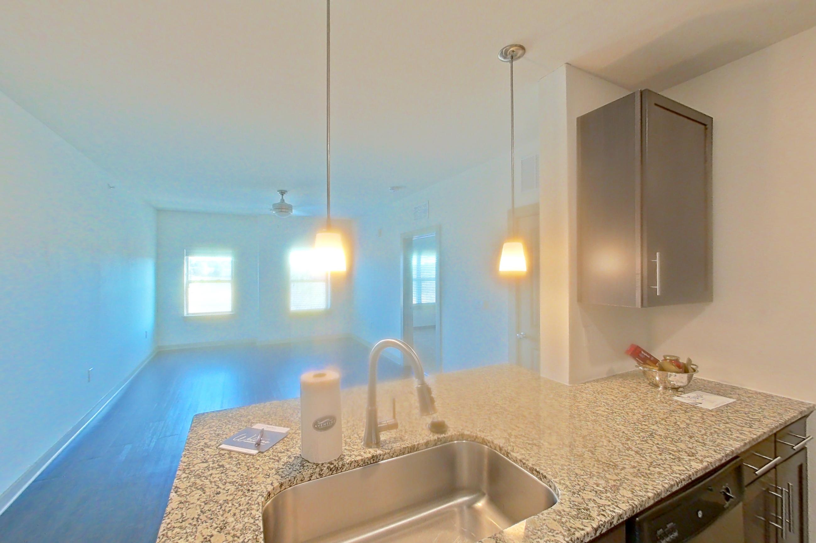 Kitchen with dark wood-finish flooring, dishwasher, electric range, light stone countertops, light wood-finish flooring, microwave, oven/range, refrigerator, and stainless steel appliances, Apartment 1-519 at Aventine Northshore