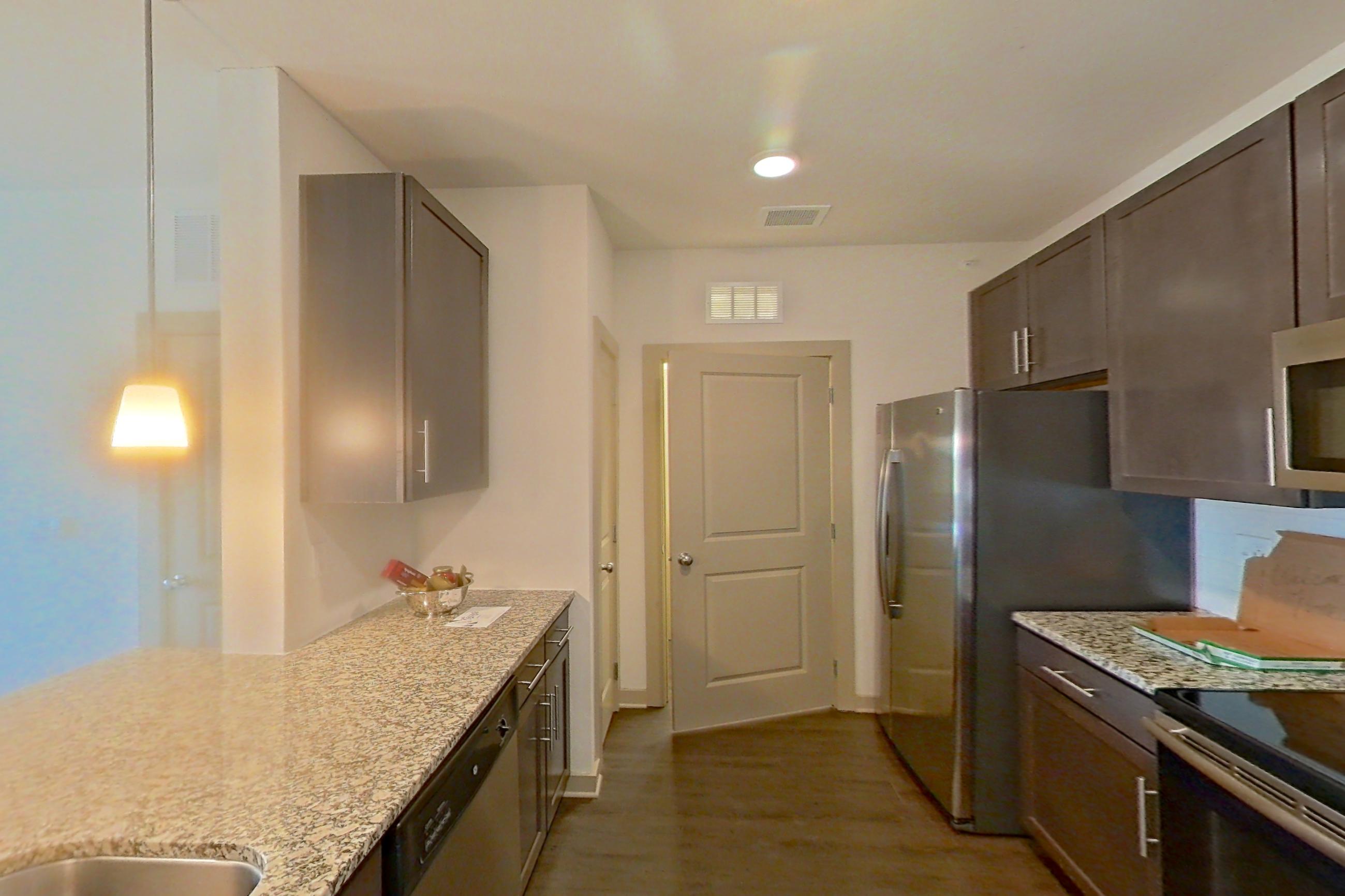Kitchen with dark wood-finish flooring, dishwasher, electric range, light stone countertops, light wood-finish flooring, microwave, oven/range, refrigerator, and stainless steel appliances, Apartment 1-519 at Aventine Northshore