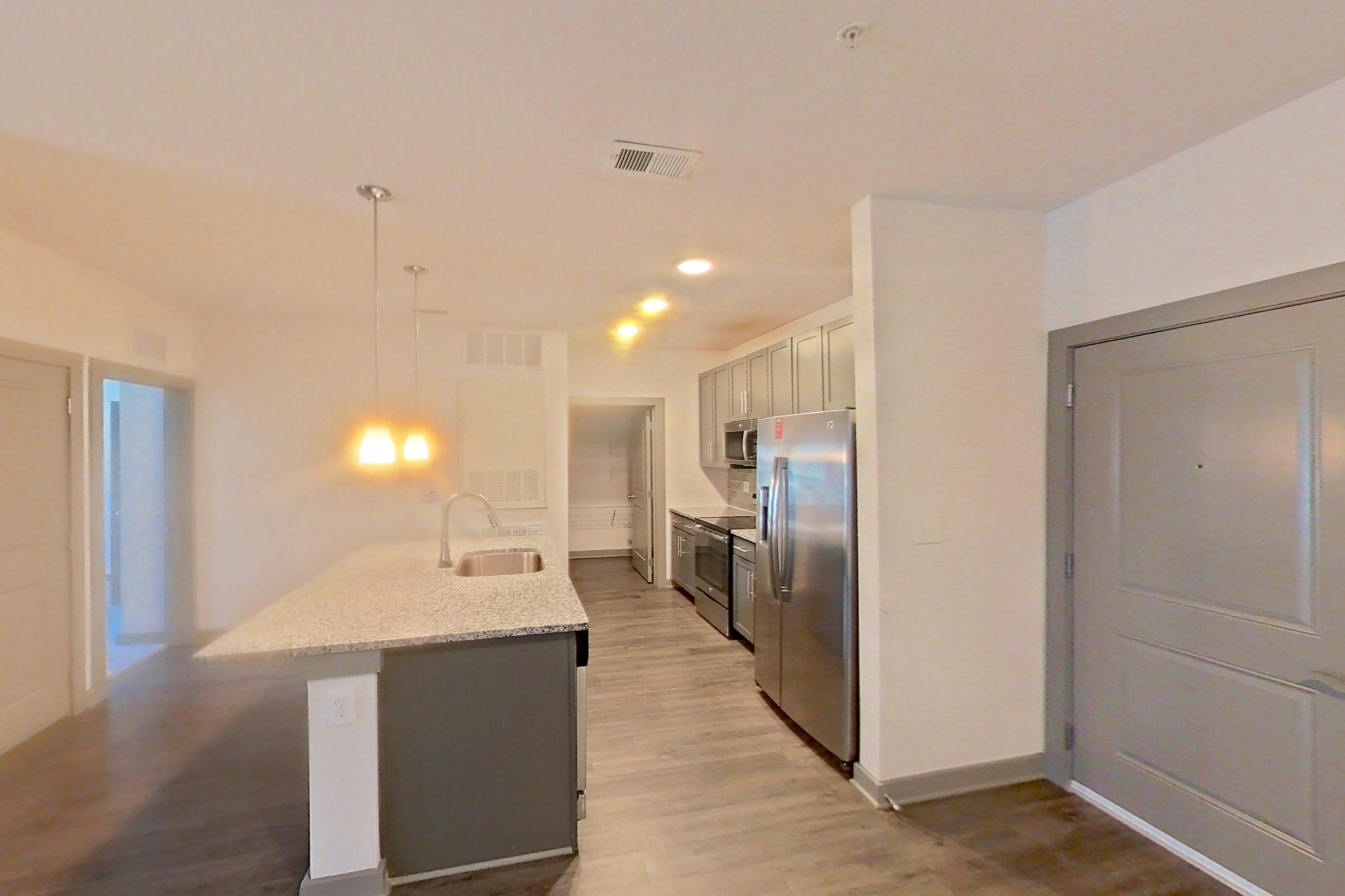 Living room with dark wood-finish flooring, electric range, light stone countertops, oven/range, refrigerator, and stainless steel appliances, Apartment 9-204 at Aventine Northshore