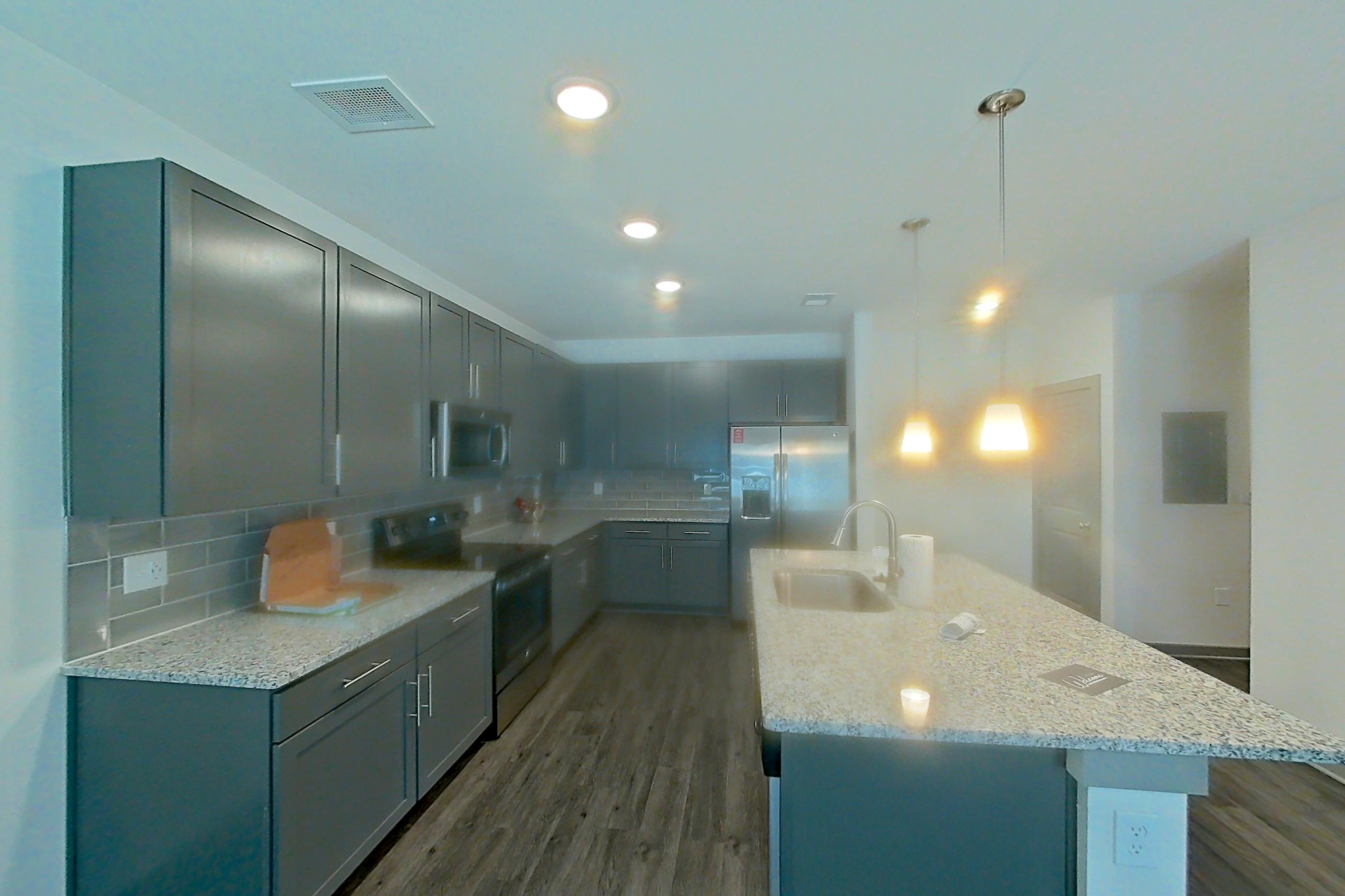 Living room with black appliances, dark wood-finish flooring, electric range, kitchen island, light stone countertops, oven/range, and refrigerator, Apartment 7-109 at Aventine Northshore
