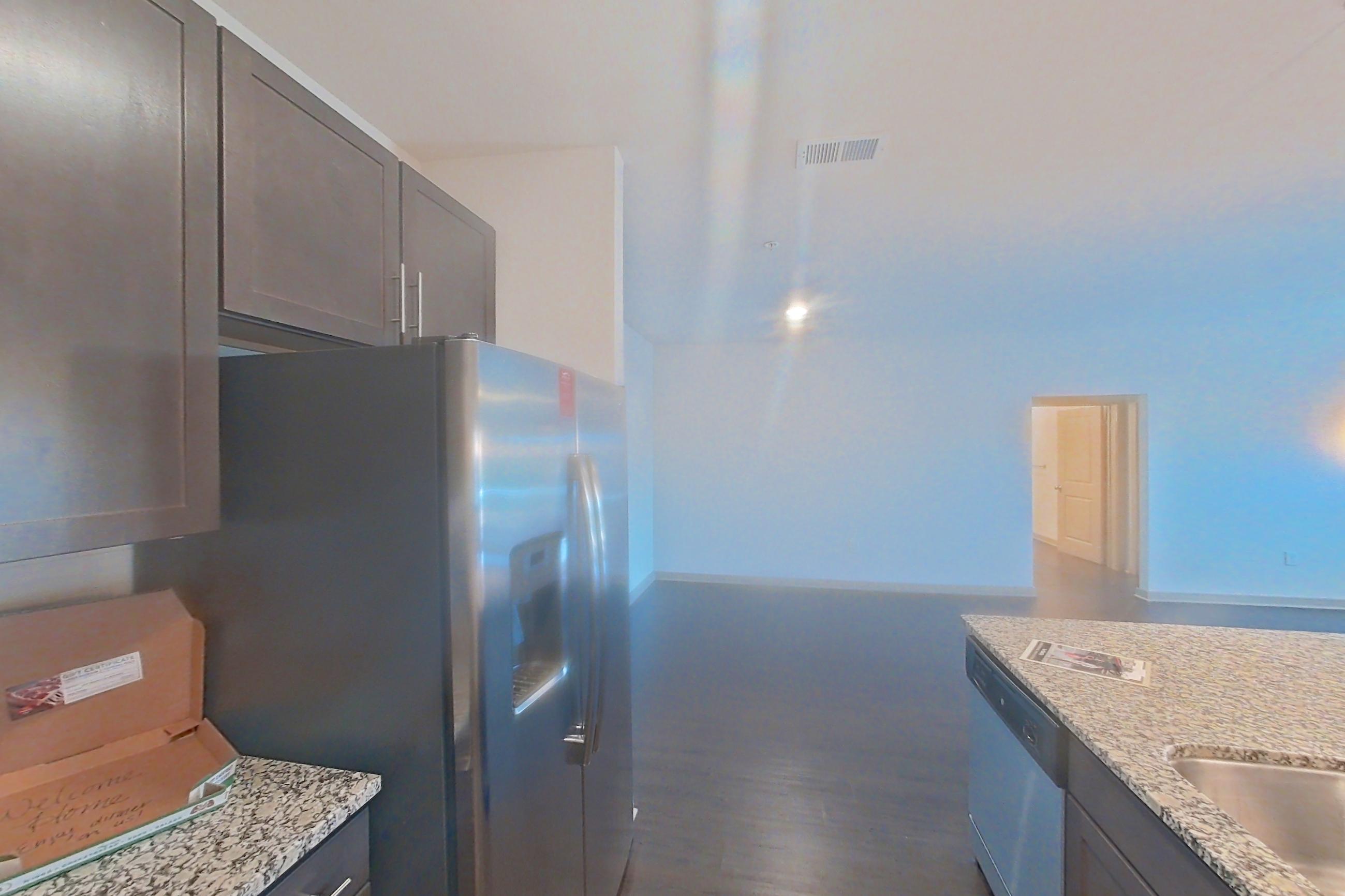 Kitchen with dark wood-finish flooring, electric range, kitchen island, light stone countertops, microwave, oven/range, refrigerator, and stainless steel appliances, Apartment 7-203 at Aventine Northshore