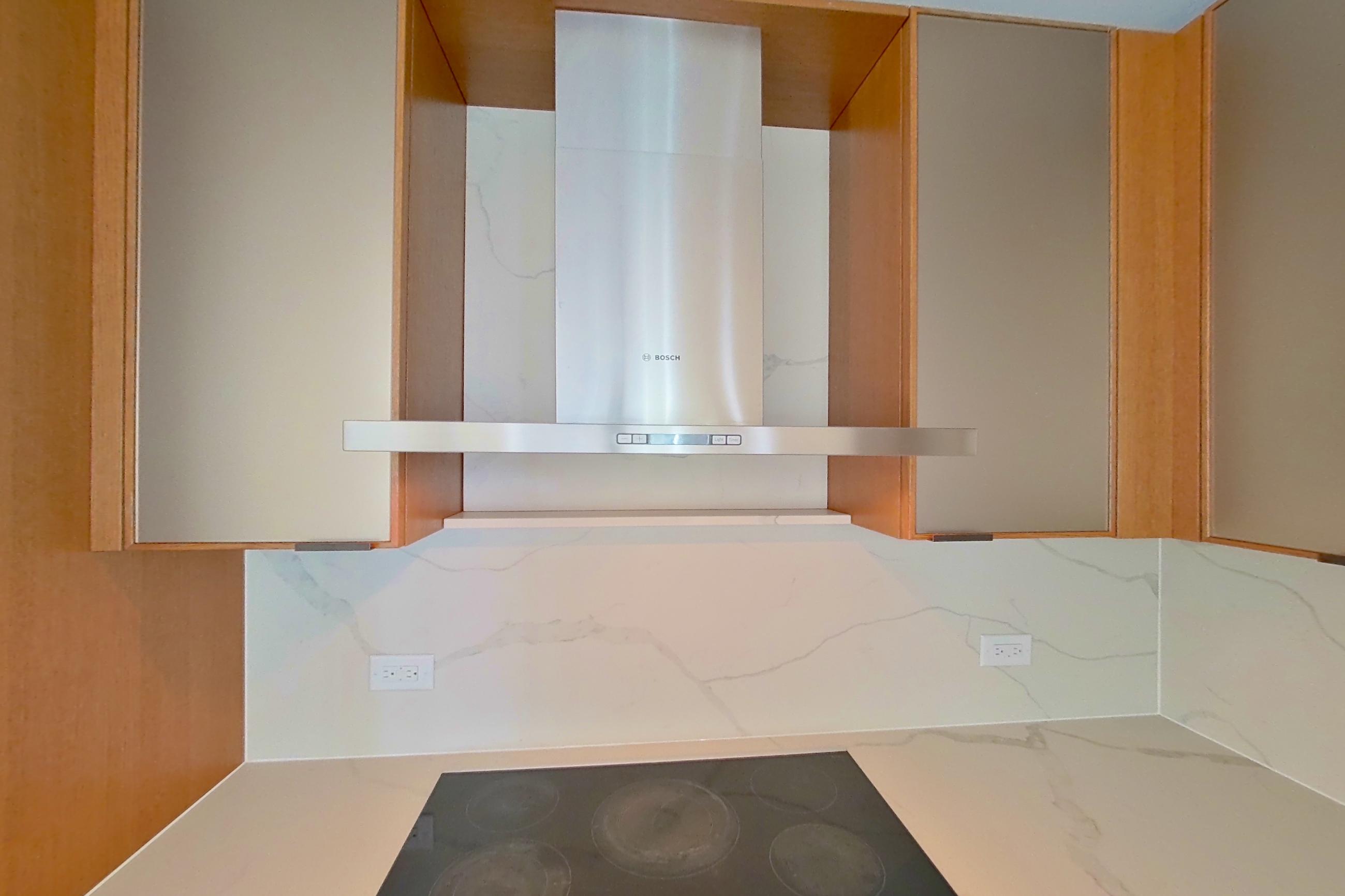 Kitchen with black appliances, cooktop, electric cooktop, light stone countertops, light wood-finish flooring, oven/range, and stainless steel appliances, Apartment 1603 at Oriana