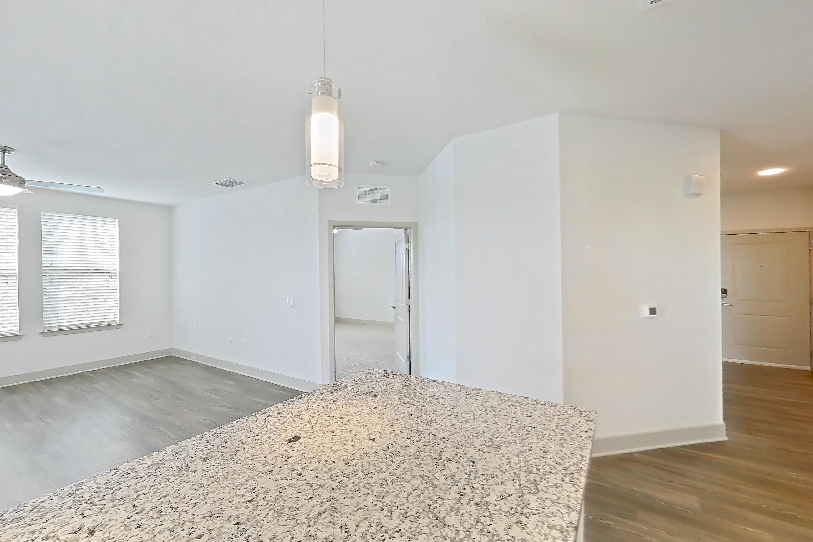 Kitchen with dark wood-finish flooring, dishwasher, electric range, light stone countertops, oven/range, refrigerator, stainless steel appliances, and water & ice dispenser, Apartment B1-201 at Lantower Grande Flats