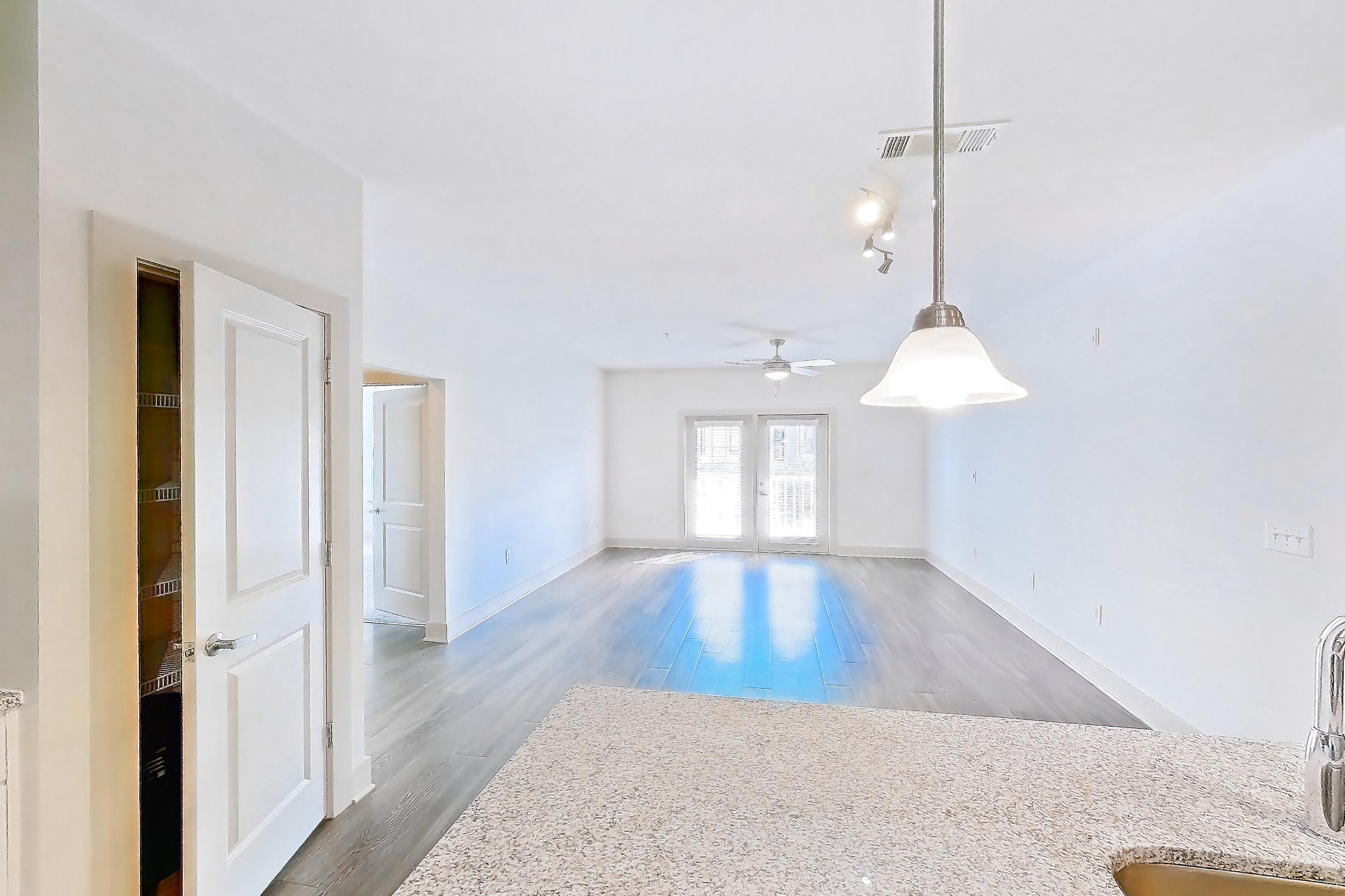 Kitchen with dark wood-finish flooring, dishwasher, electric range, light countertops, light stone countertops, light wood-finish flooring, microwave, oven/range, and stainless steel appliances, Apartment 1208 at Lantower Waverly